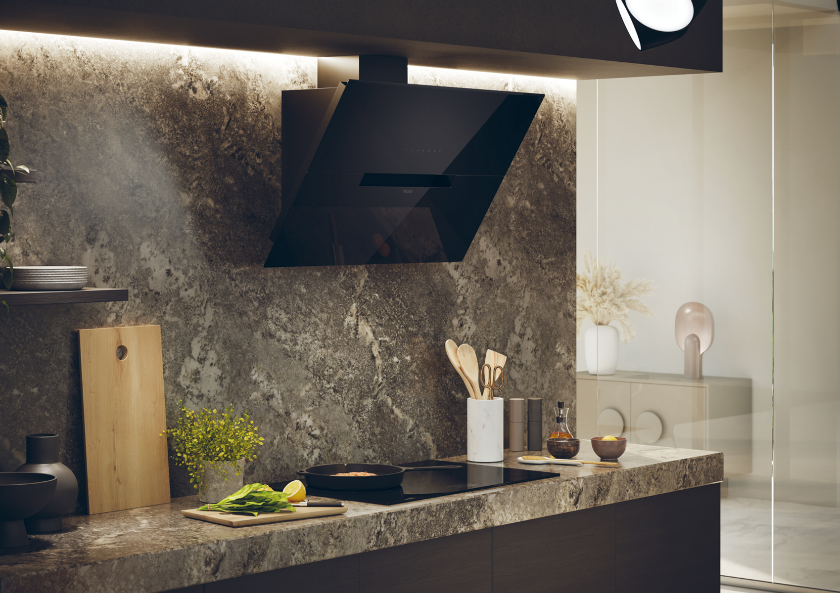 Cocina moderna con campana extractora negra, encimera con utensilios de cocina y comida. Salpicadero y armarios de mármol, puerta de cristal.