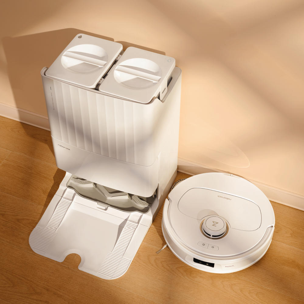 Biały robot odkurzający i stacja dokująca na drewnianej podłodze. Stacja ma dwa przedziały.