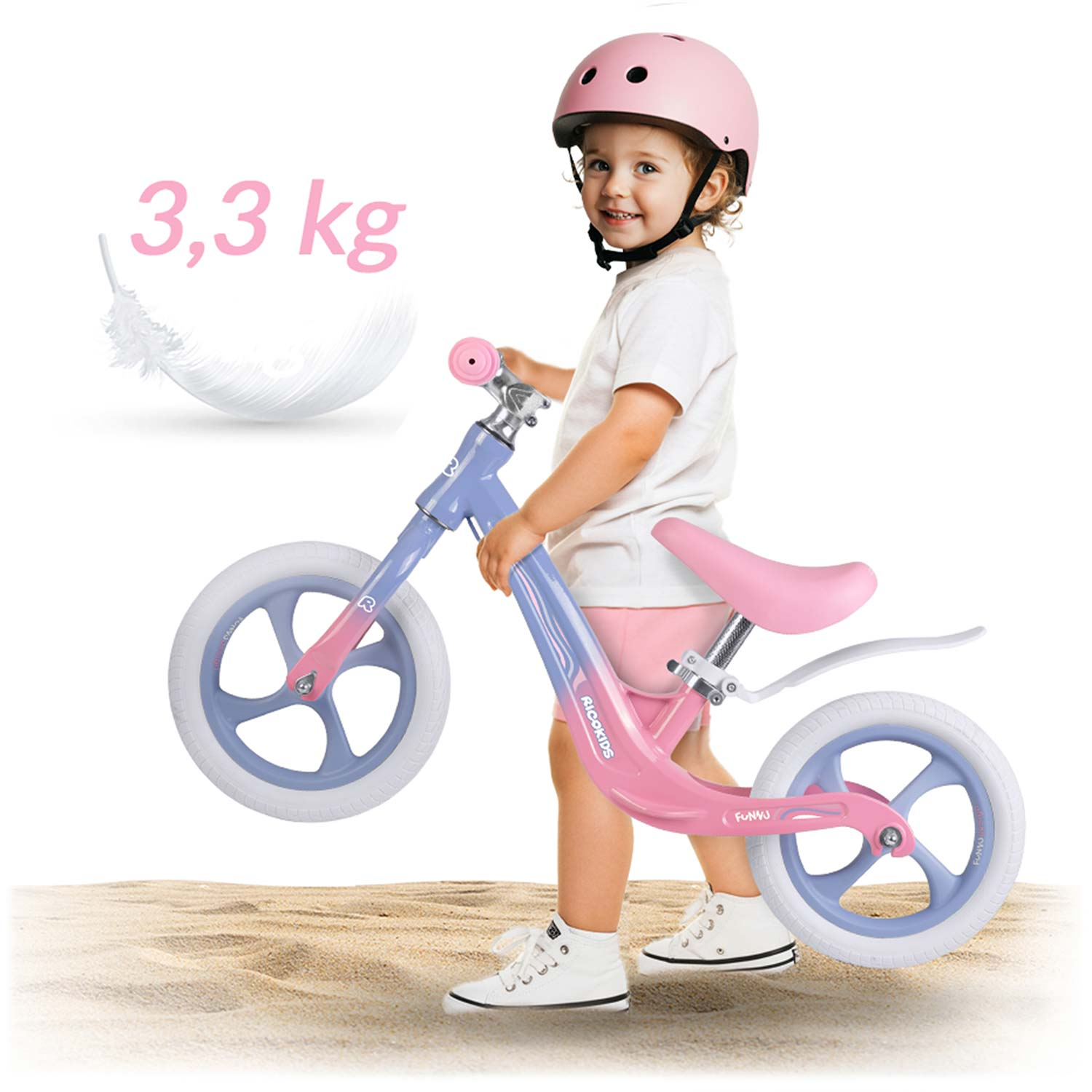 Dziecko w różowym kasku trzyma różowo-niebieski rowerek biegowy. Tekst mówi 3,3 kg. Są na piasku.