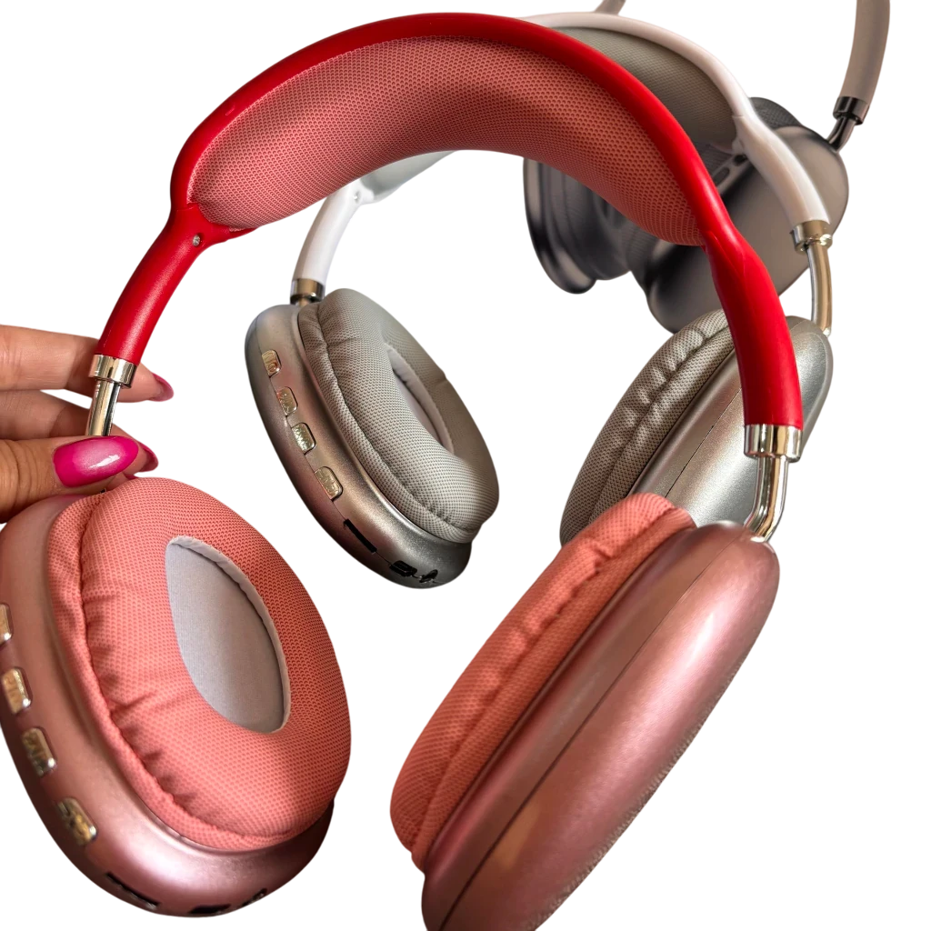 Una mano sostiene auriculares rosas y rojos. Otros dos pares de auriculares son visibles en el fondo.