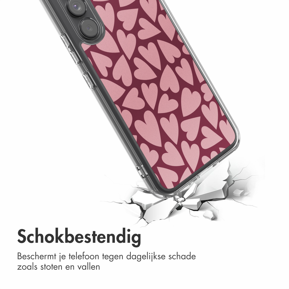 Un téléphone avec une coque à motifs de cœurs roses casse une surface. La coque du téléphone montre l'impact et les mots 'Schokbestendig' apparaissent.