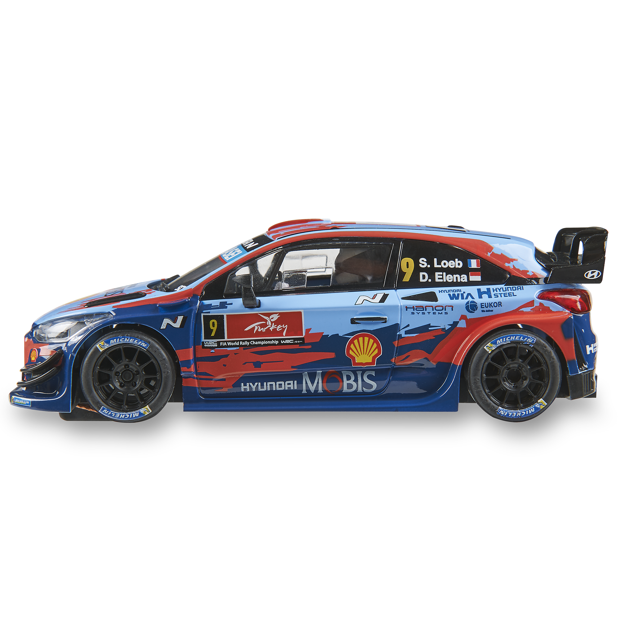Un modelo de coche de rally Hyundai azul y rojo. Tiene logotipos de patrocinadores, neumáticos Michelin y el número 9. Fondo blanco.