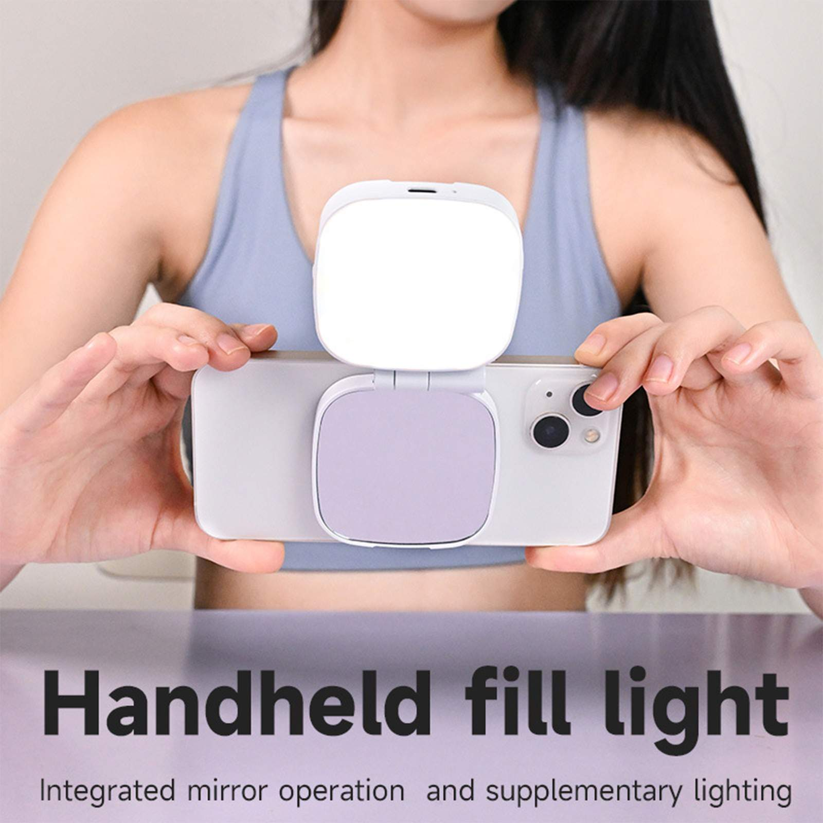 Eine Person hält ein Telefon mit einem Licht- und Spiegelaufsatz. Der Text lautet 'Handheld fill light'.