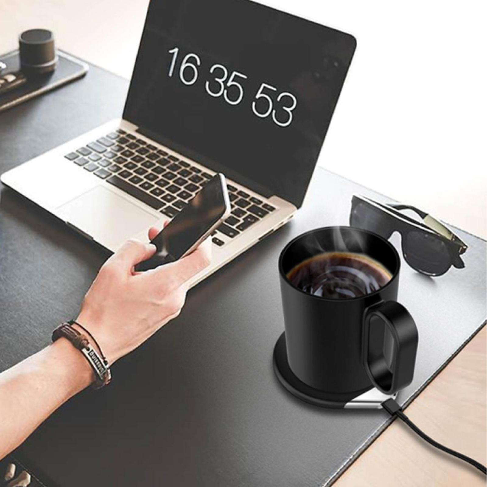 Ein Laptop mit Zeitanzeige, eine schwarze Kaffeetasse, ein Telefon und eine Brille auf einem Schreibtisch.