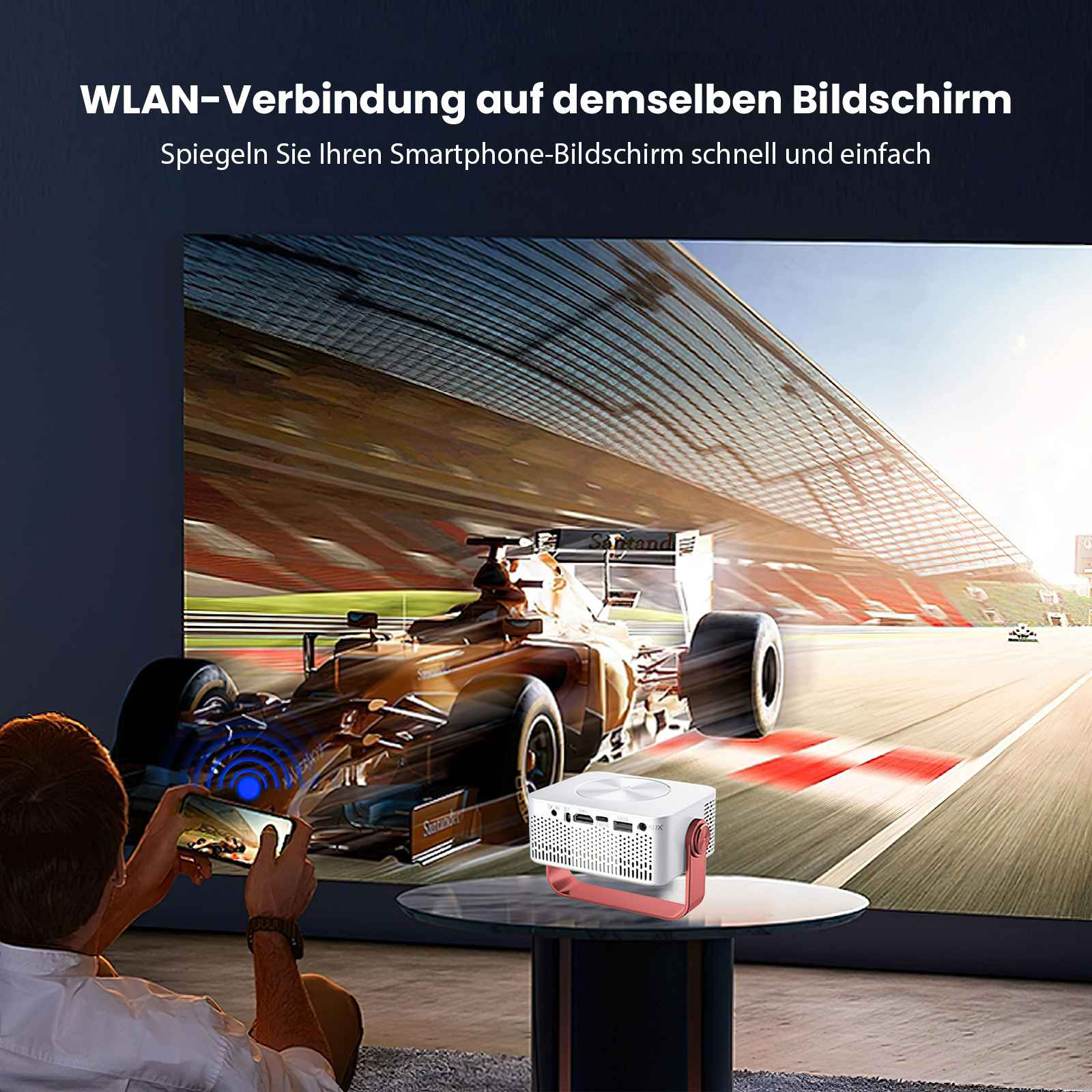 Mann spiegelt den Telefonbildschirm. Autorennen auf großem Bildschirm. Ein Projektor steht auf einem Tisch.