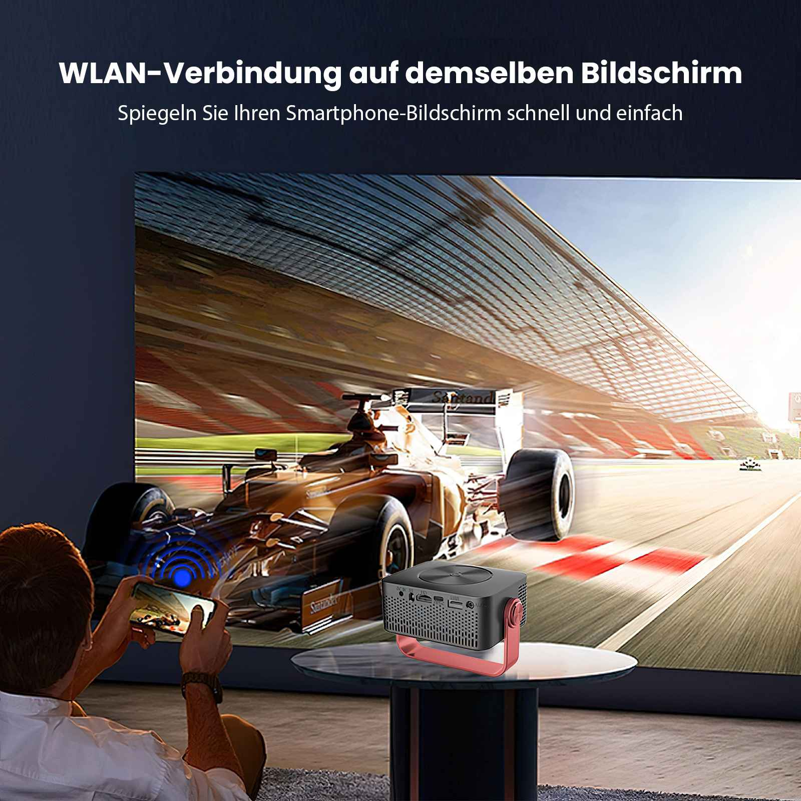 Eine Person spiegelt ein Rennwagenvideo von einem Telefon auf einen Bildschirm. Ein Projektor steht auf einem Tisch.