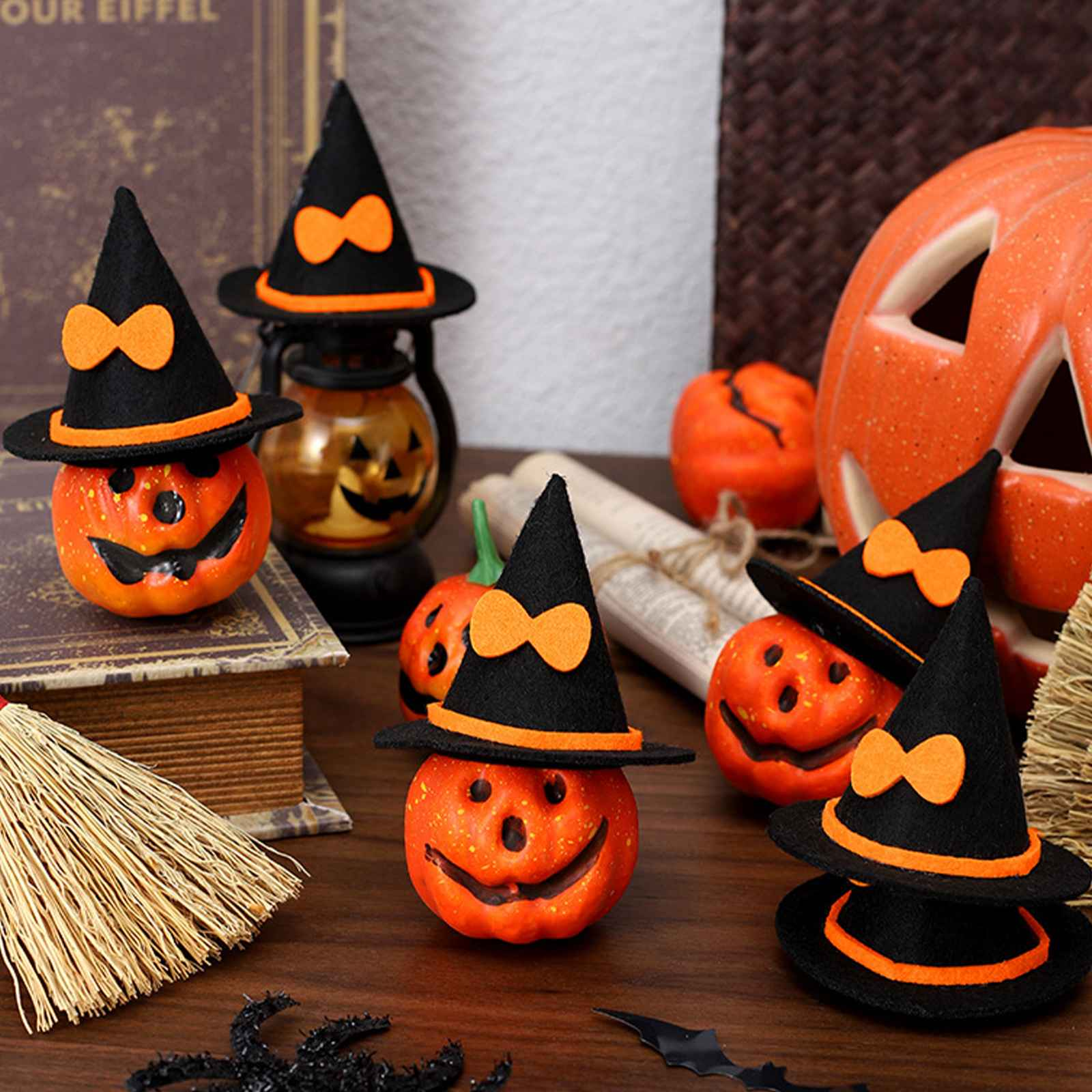 Eine Halloween-Szene mit Kürbissen mit Hexenhüten, einer Laterne und anderen Dekorationen auf einem Holztisch.