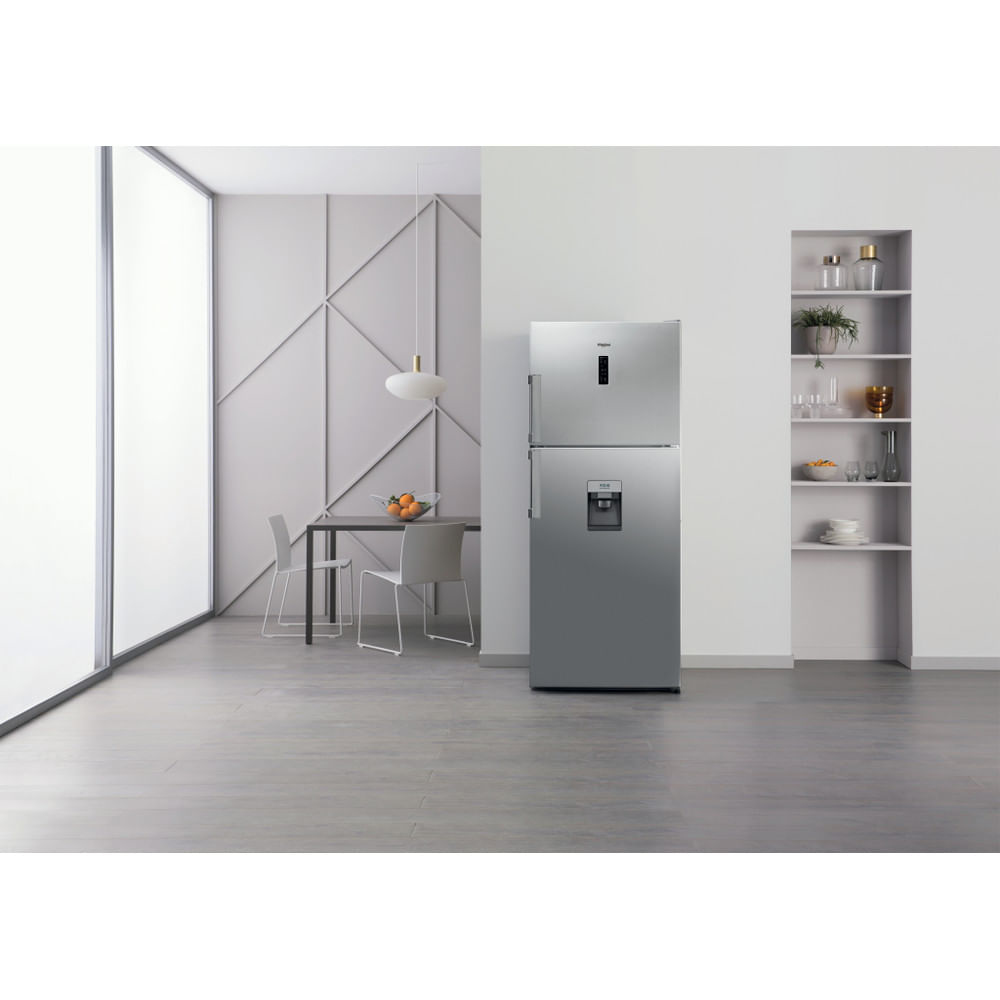 Una cucina moderna con un frigorifero in acciaio inossidabile è il punto focale. Sono visibili un tavolo da pranzo con sedie e una finestra.