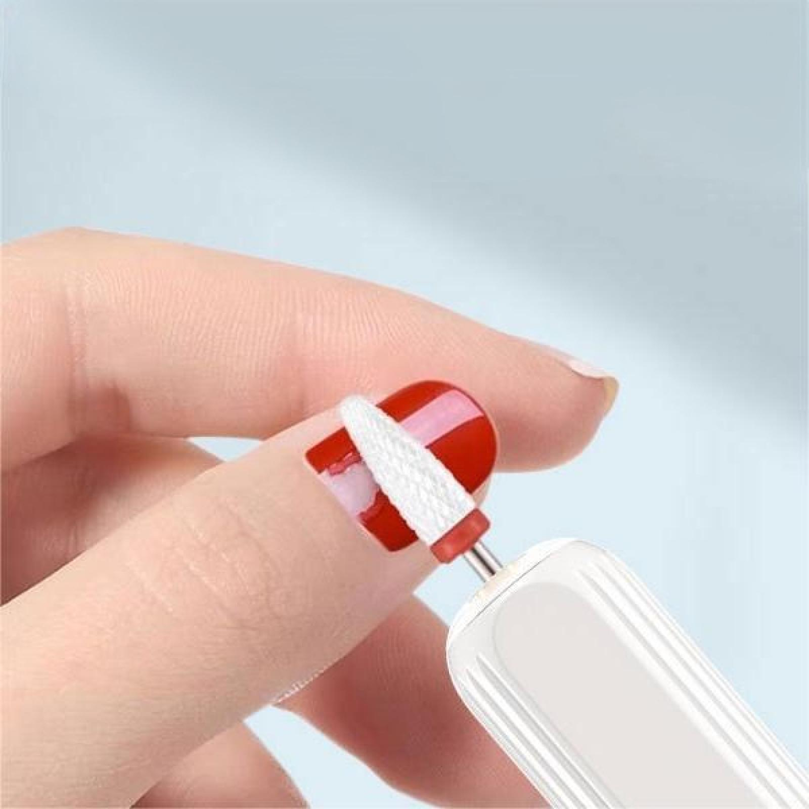 Eine Hand, die einen rot lackierten Nagel mit einem weißen Bohrer hält, Teil eines Nagelpflegeprozesses.