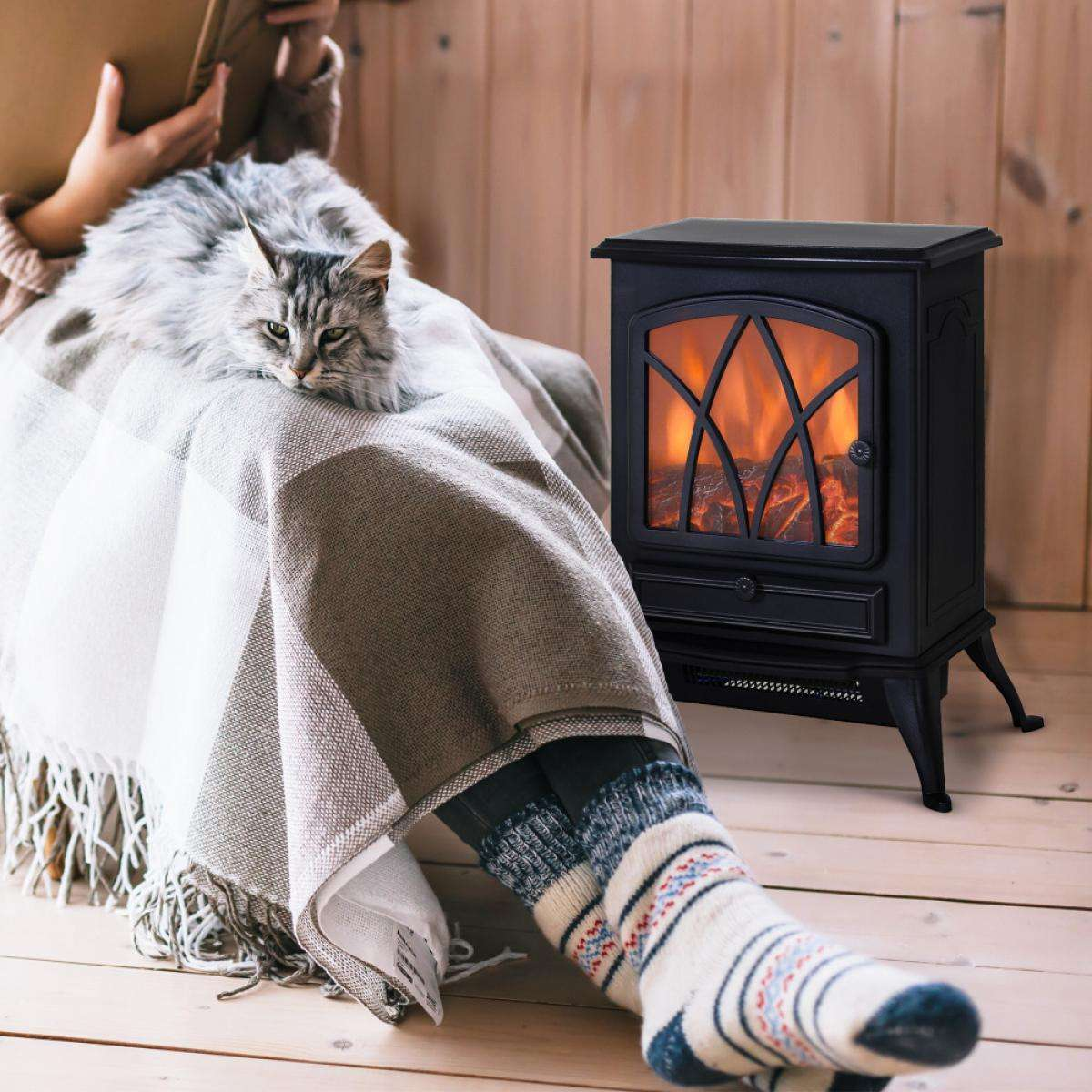 Eine Person liest, eine Katze auf einer Decke, ein Kamin. Warme Socken. Gemütliche Innenumgebung.