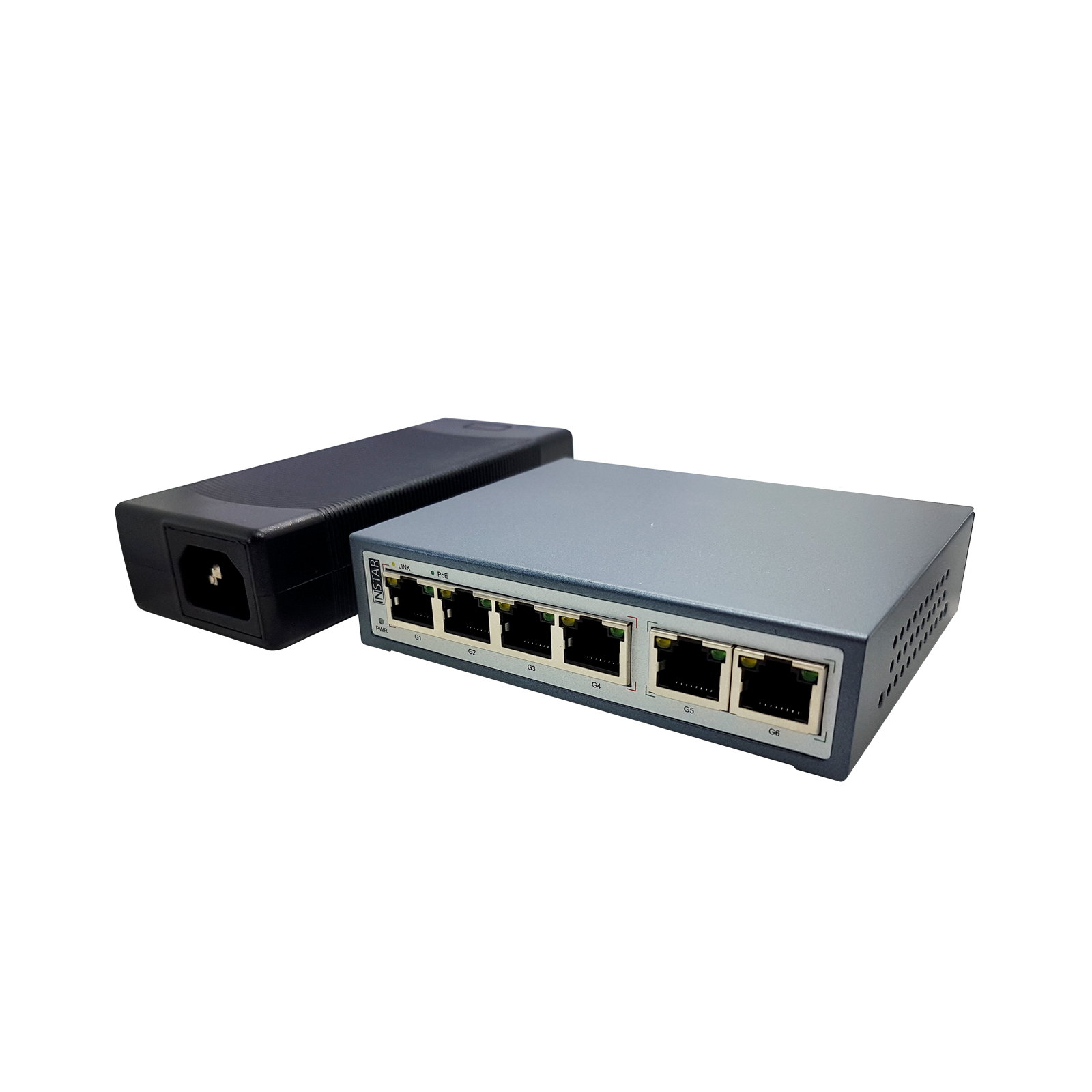 Ein Netzwerk-Switch und ein Netzteil liegen auf weißem Grund. Der Switch ist grau, das Netzteil ist schwarz.
