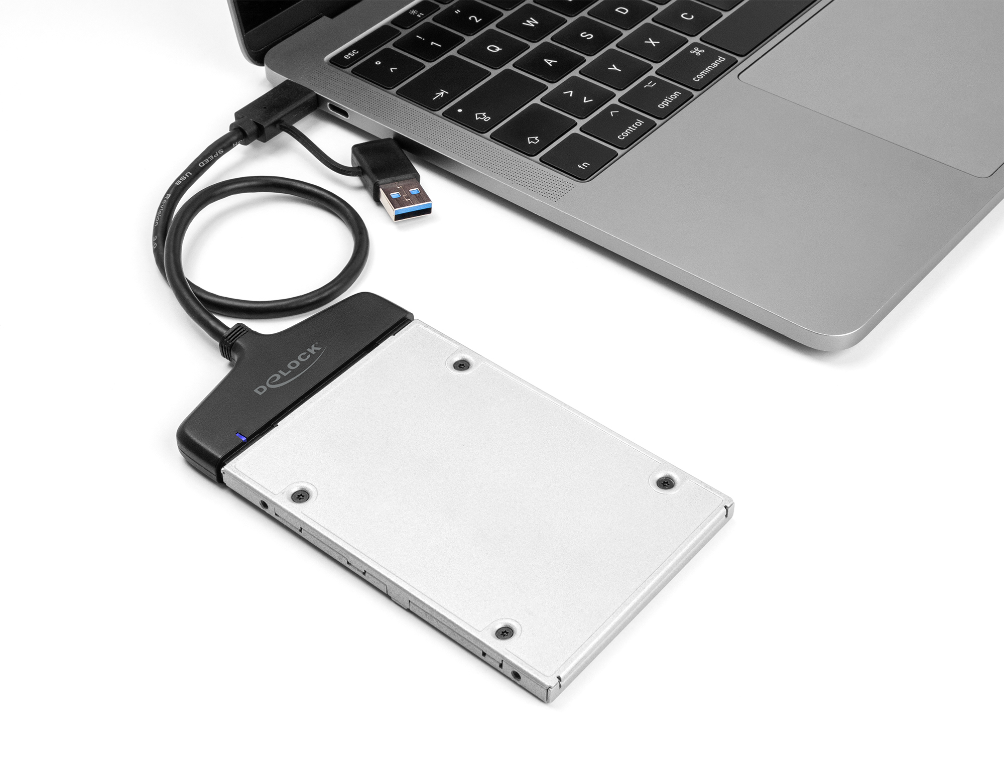 Laptop jest podłączony do zewnętrznego dysku twardego za pomocą kabla USB. Dysk jest srebrny, marki 'DOLOCK'.