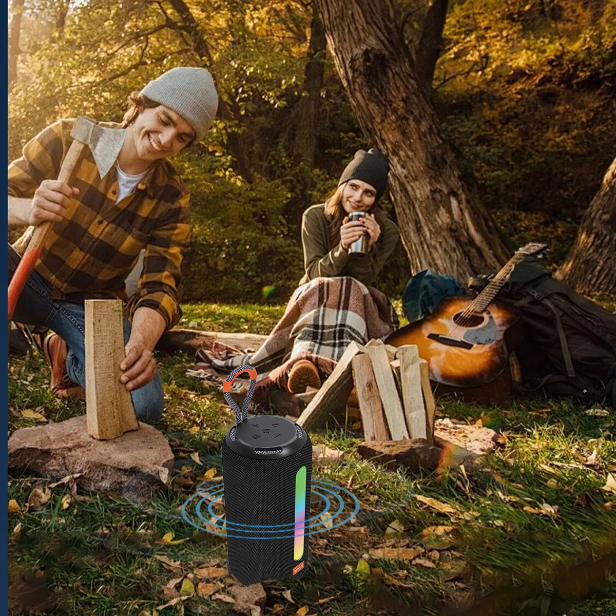 Ludzie biwakują z głośnikiem na pierwszym planie. Jedna osoba rąbie drewno, druga pije kawę. Widoczne są gitara i plecak.