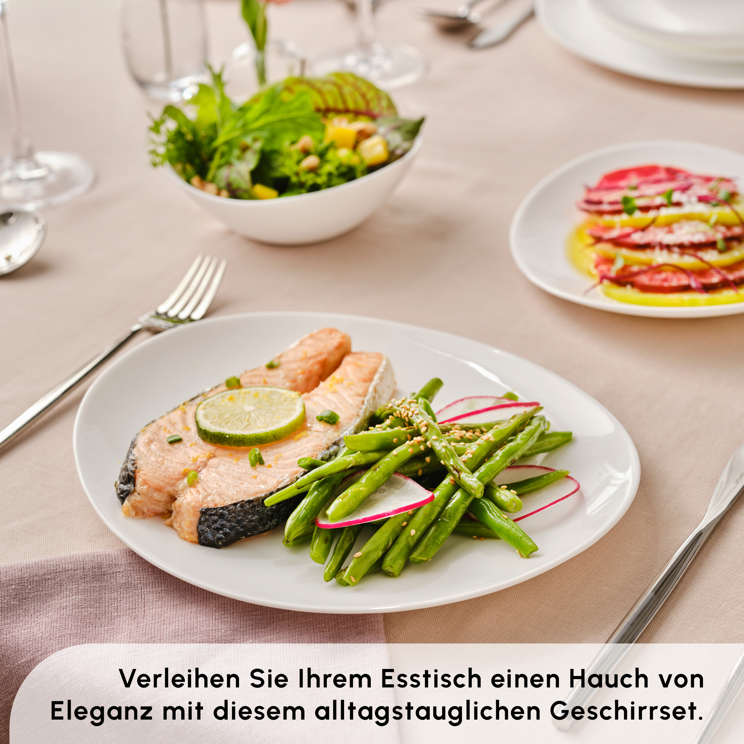 Salmone con lime, fagiolini e insalata su piatto bianco. Tavola apparecchiata con posate e bicchieri.