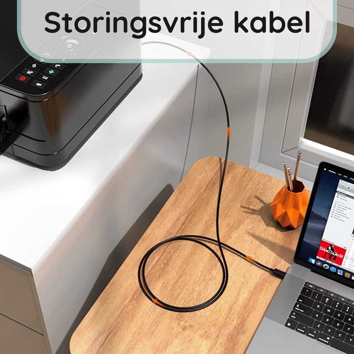 Een zwarte kabel met oranje accenten ligt op een houten tafel, verbonden met een laptop en een printer. Een oranje vaas met potloden is zichtbaar.