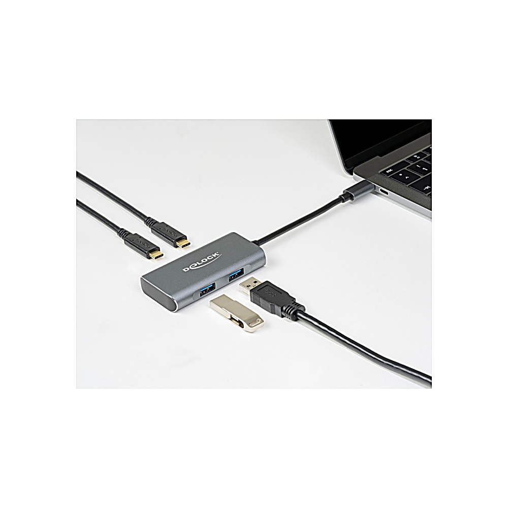 Un hub USB argentato è collegato a un laptop. Una chiavetta USB e un altro cavo USB sono vicini. Altri due cavi a sinistra.