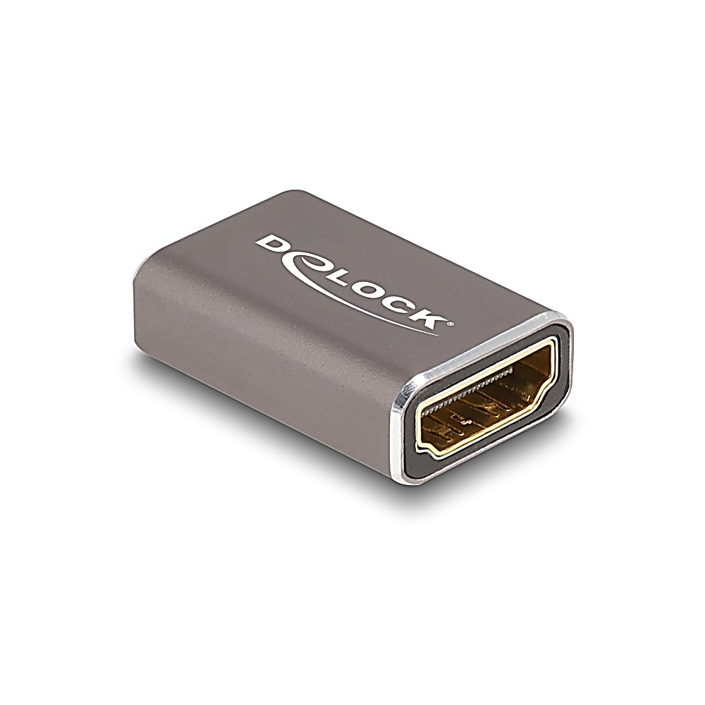 Srebrny adapter HDMI z logo 'DeLOCK'. Jest prostokątny ze złotym portem.