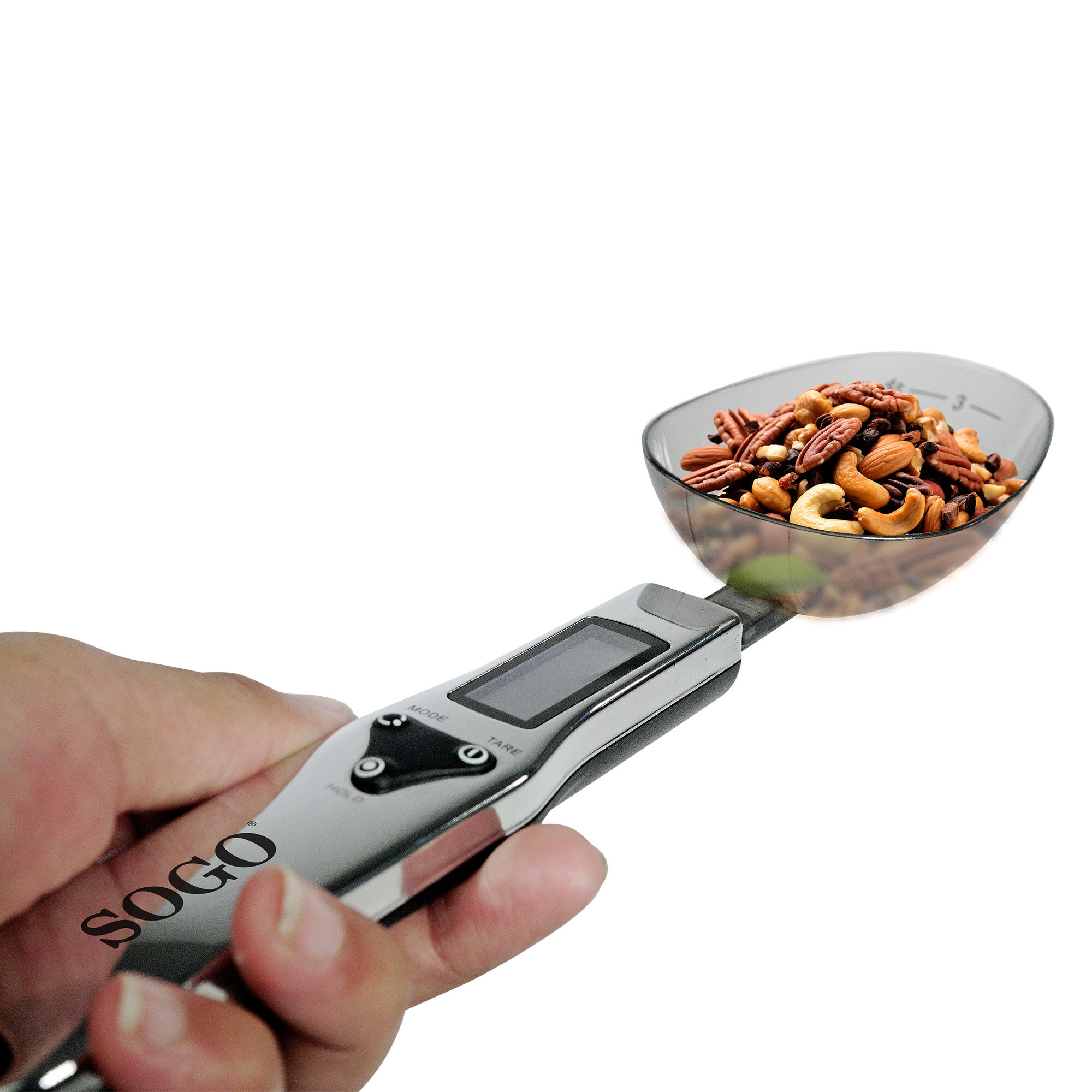 Una mano sostiene una balanza con nueces en una cuchara. La balanza es plateada y tiene una pantalla digital. El fondo es blanco.
