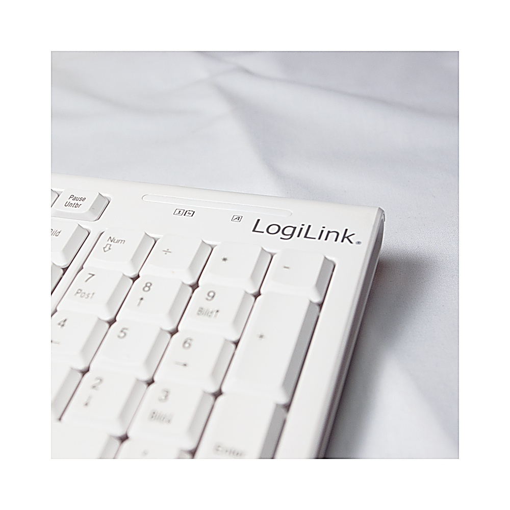 Zbliżenie białej klawiatury LogiLink. Widoczne klawisze z cyframi i symbolami. Tło to biała tkanina.