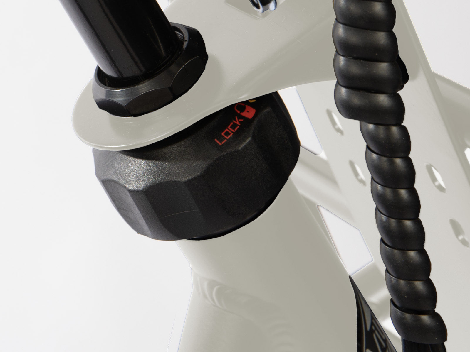 Close-up van een wit fietsframe met zwarte componenten. Een zwart slot is zichtbaar met het woord 'LOCK' in het rood. Een zwarte kabel loopt ernaast.