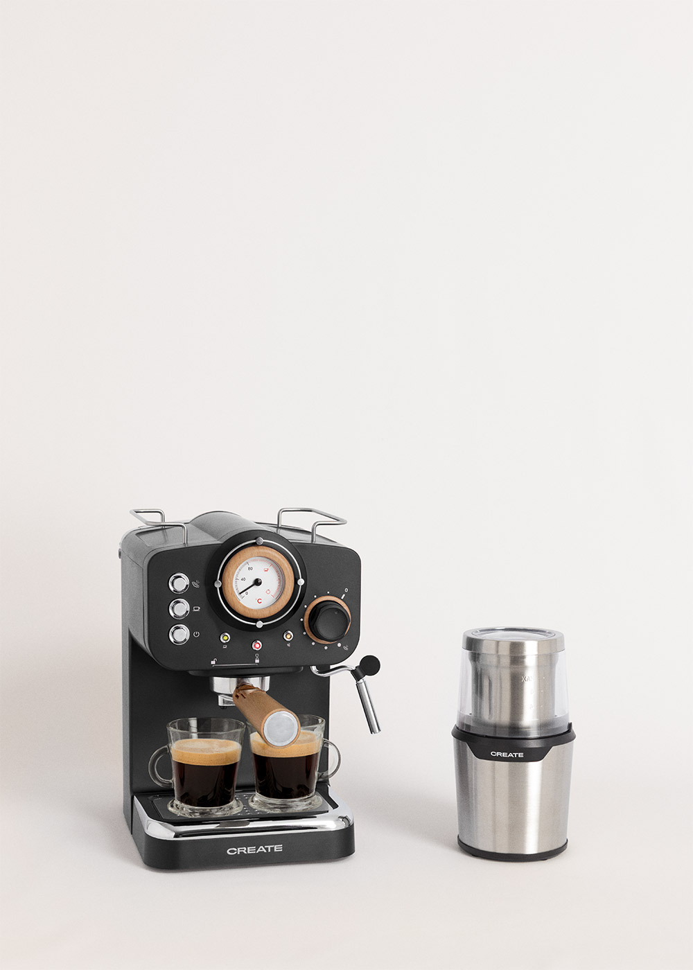 Máquina de espresso negra con dos tazas de café y un molinillo sobre un fondo blanco.