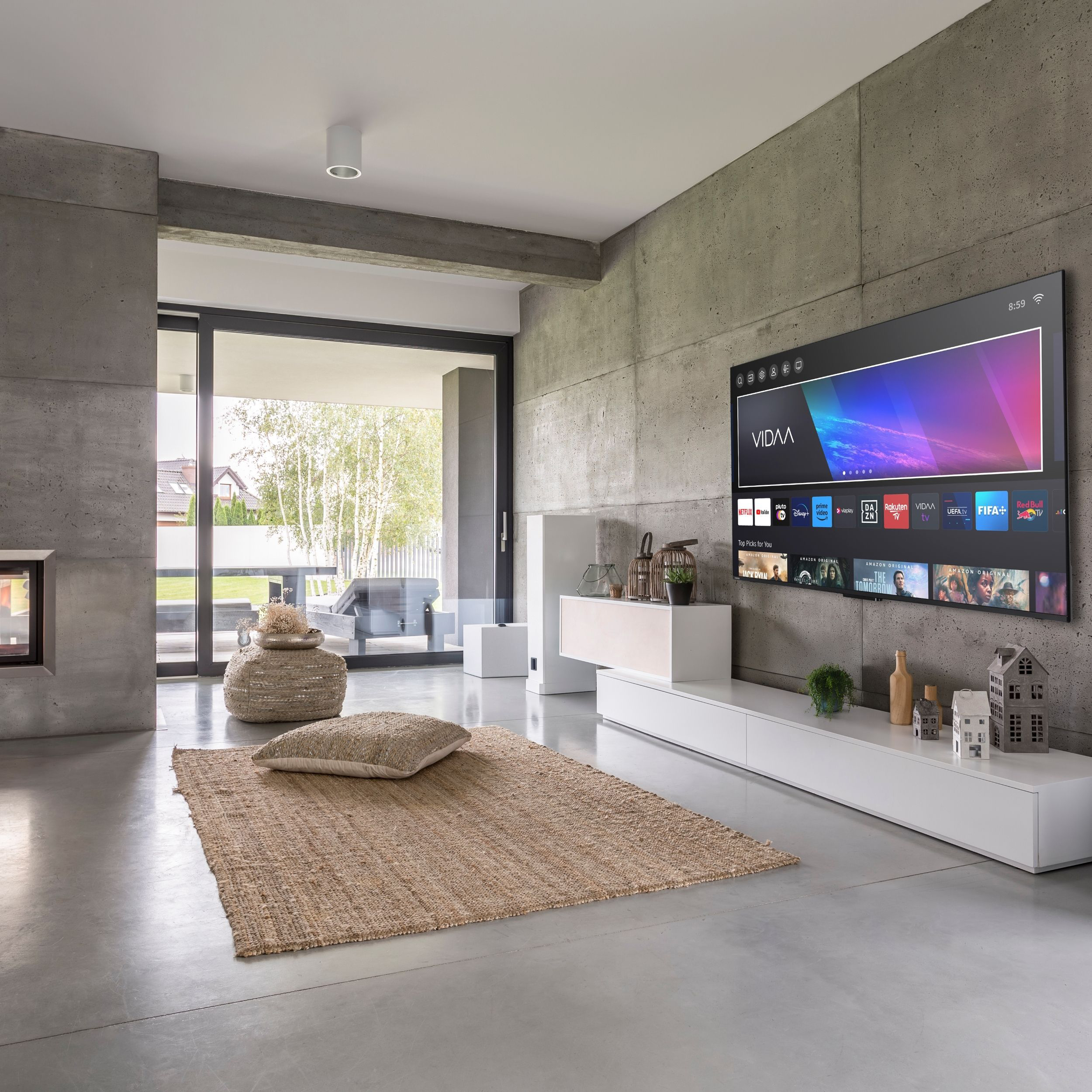 Modernes Wohnzimmer mit Betonwänden, Fernseher, Teppich und großem Fenster mit Blick ins Grüne.