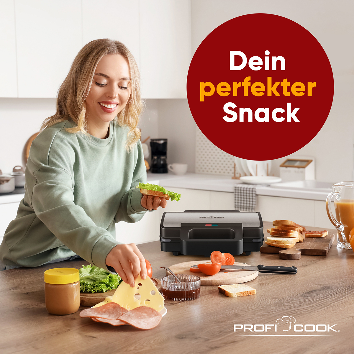 Frau bereitet Sandwich mit Käse, Tomaten und Salat zu. Sandwichmaker und Zutaten auf dem Tisch. Text: Dein perfekter Snack.
