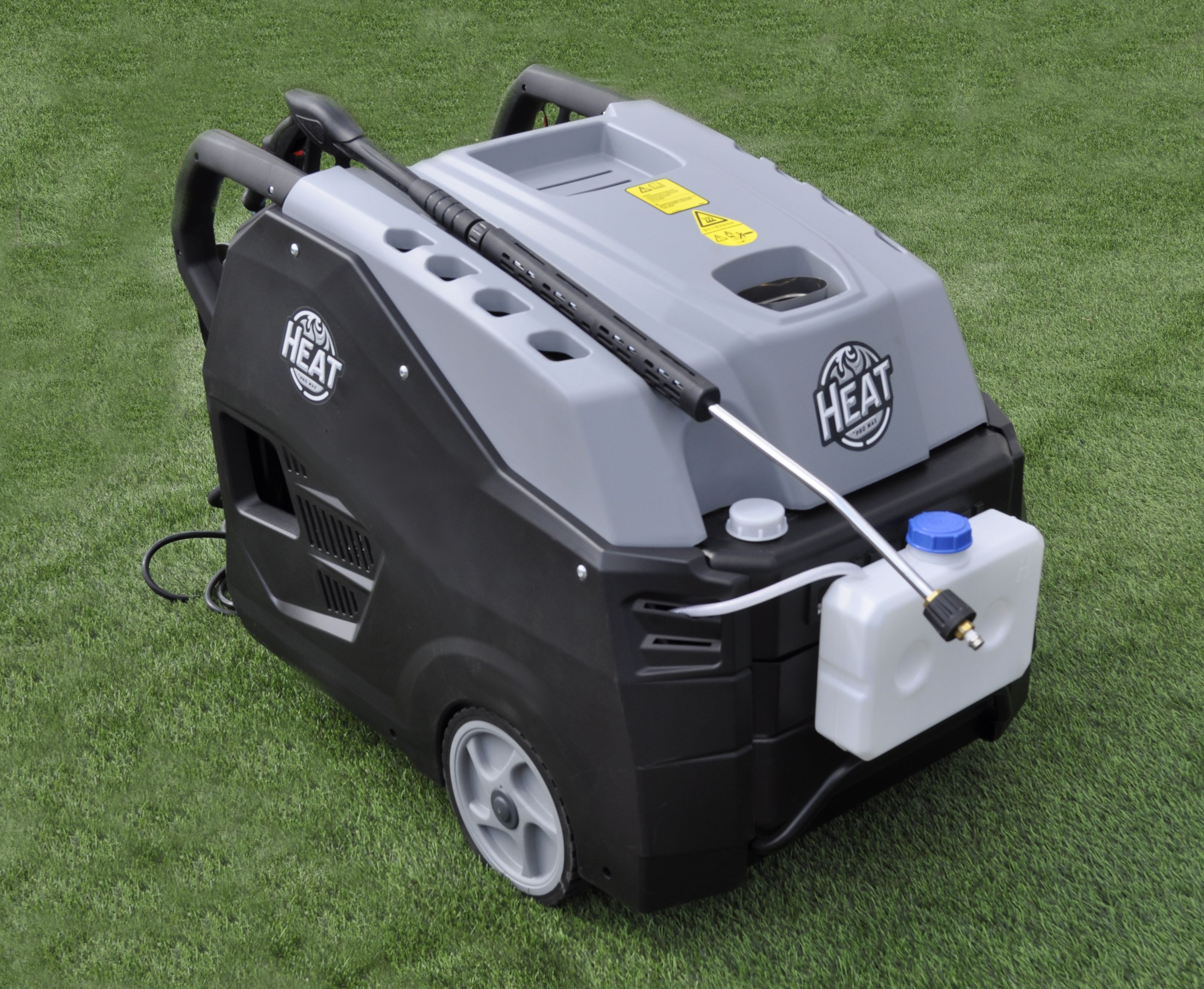 Ein schwarz-grauer Hochdruckreiniger auf grünem Gras. Er hat einen Wassertank und eine Düse. Der Markenname "HEAT" ist sichtbar.