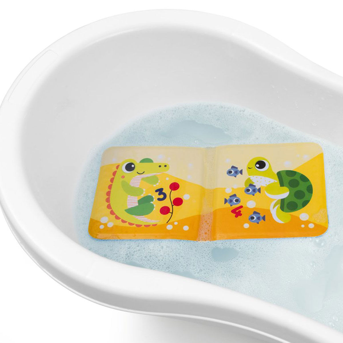 Żółta książeczka do kąpieli z postaciami z kreskówek unosi się w białej wannie wypełnionej wodą z mydłem. Książka przedstawia aligatora i żółwia.