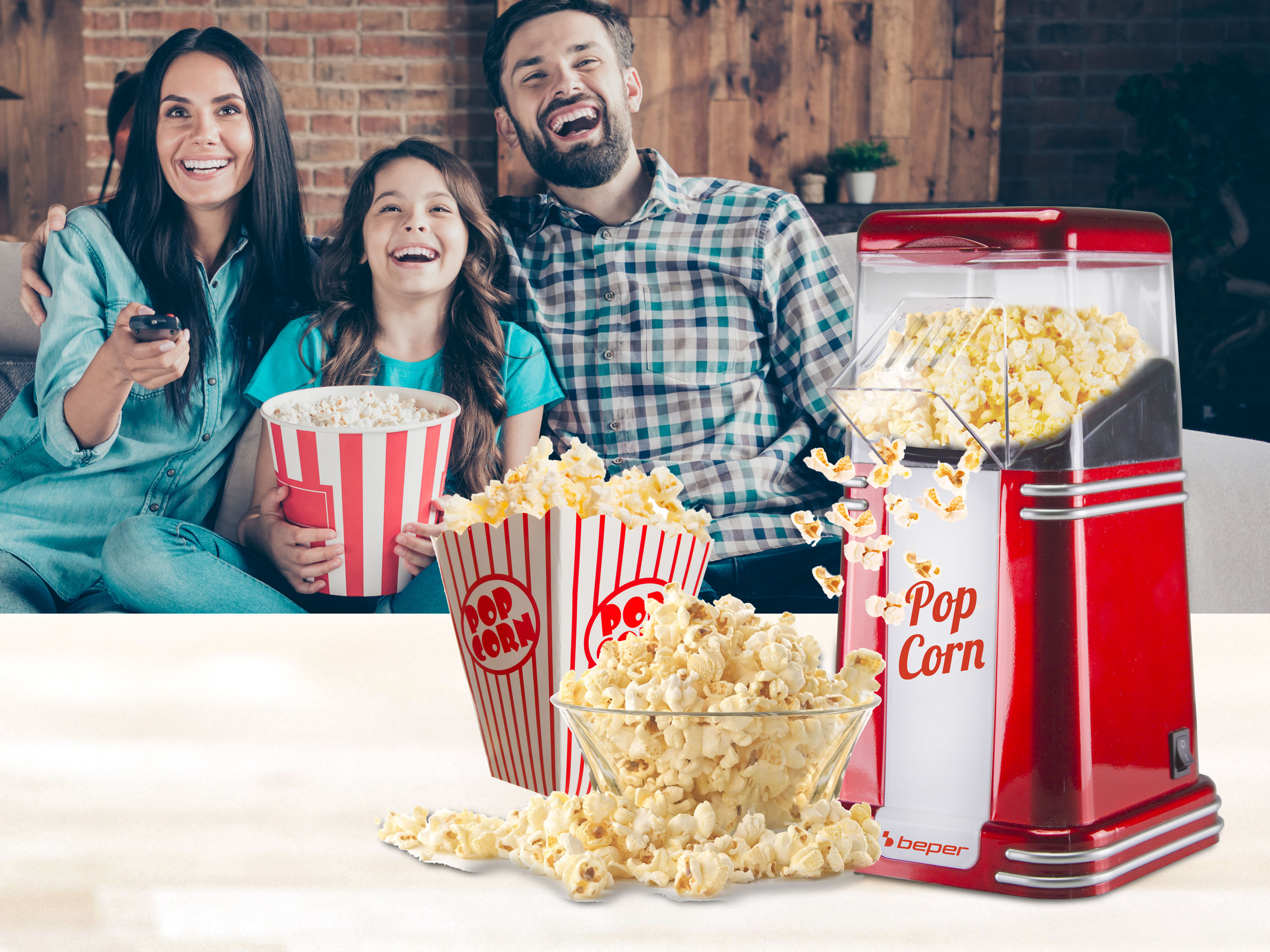 Famiglia che si gode i popcorn. Una macchina per popcorn rossa e due secchielli per popcorn in primo piano. La famiglia sorride.