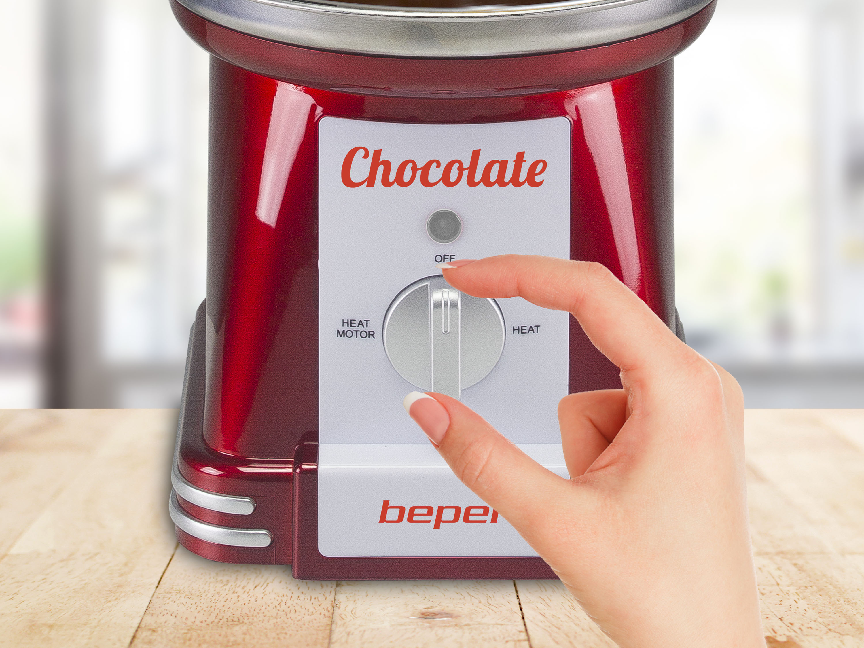 Una cioccolatiera rossa con una mano che gira la manopola del calore. La parola 'Chocolate' è visibile.