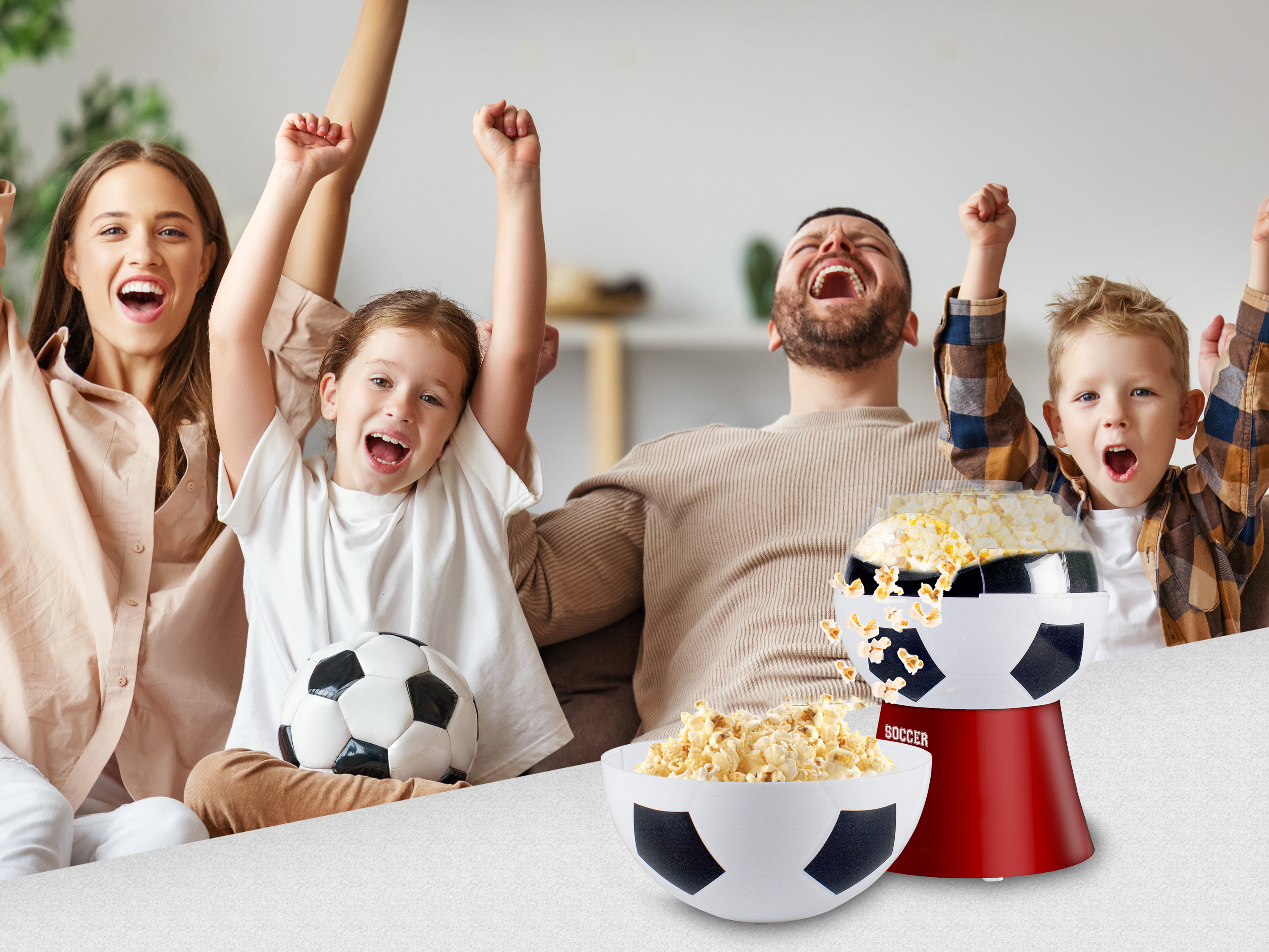 Famiglia che fa il tifo, macchina per popcorn, pallone da calcio. Una donna, una ragazza, un uomo e un ragazzo alzano le mani.