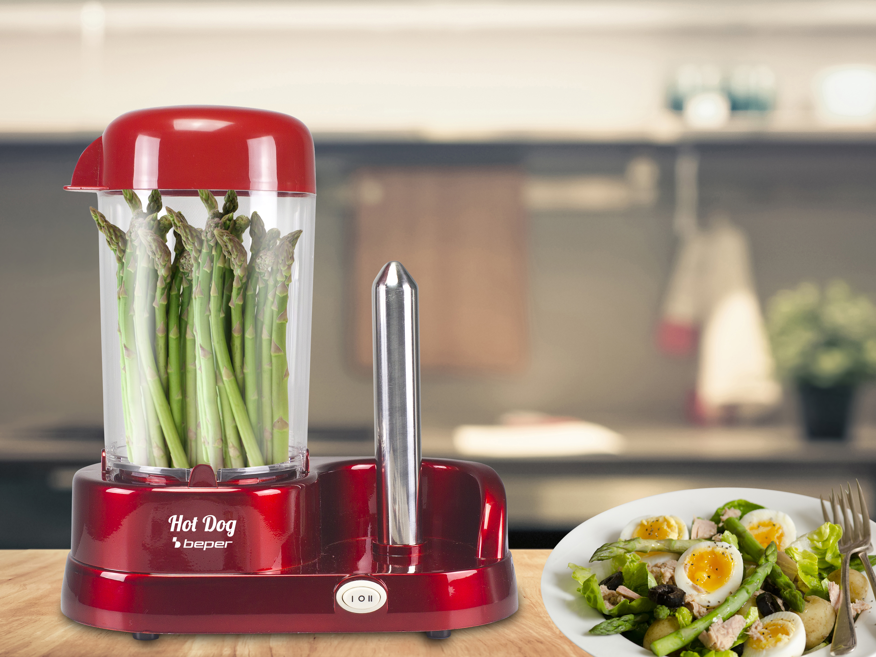Un'affettatrice rossa per hot dog con asparagi, un'insalata con uova e uno sfondo sfocato della cucina.