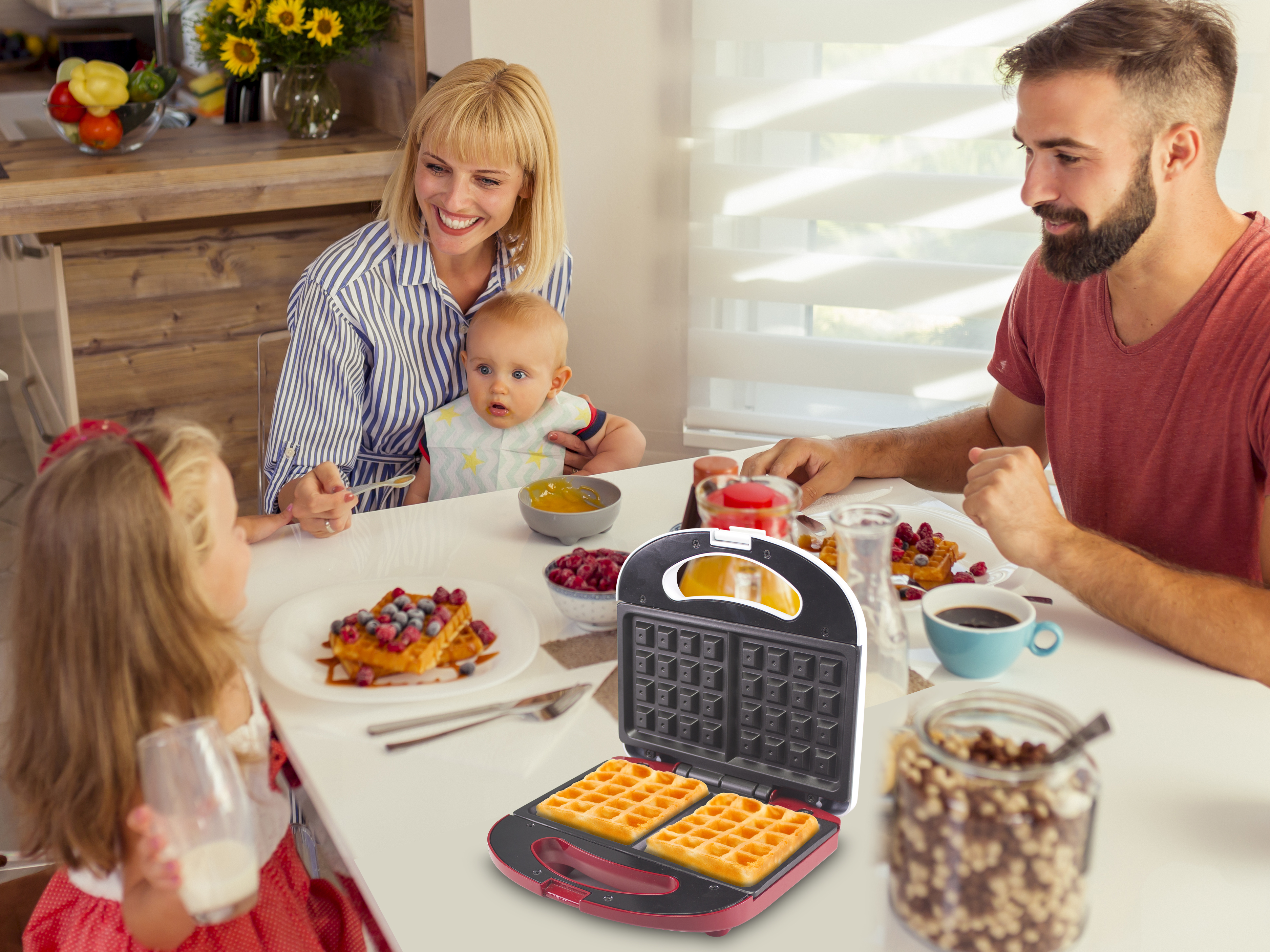 Colazione in famiglia. Vengono preparati i waffle. Le persone mangiano waffle, bacche, caffè. Waffle maker sul tavolo.