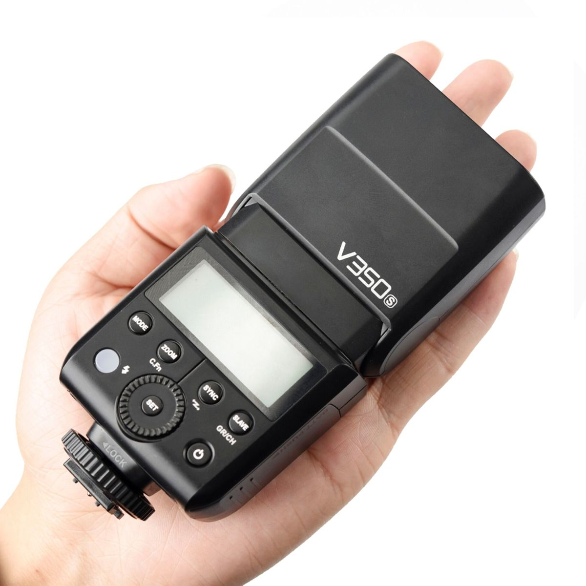 Un flash d'appareil photo noir, étiqueté V350S, est tenu dans une main. Des boutons et un écran sont visibles. Le fond est blanc.