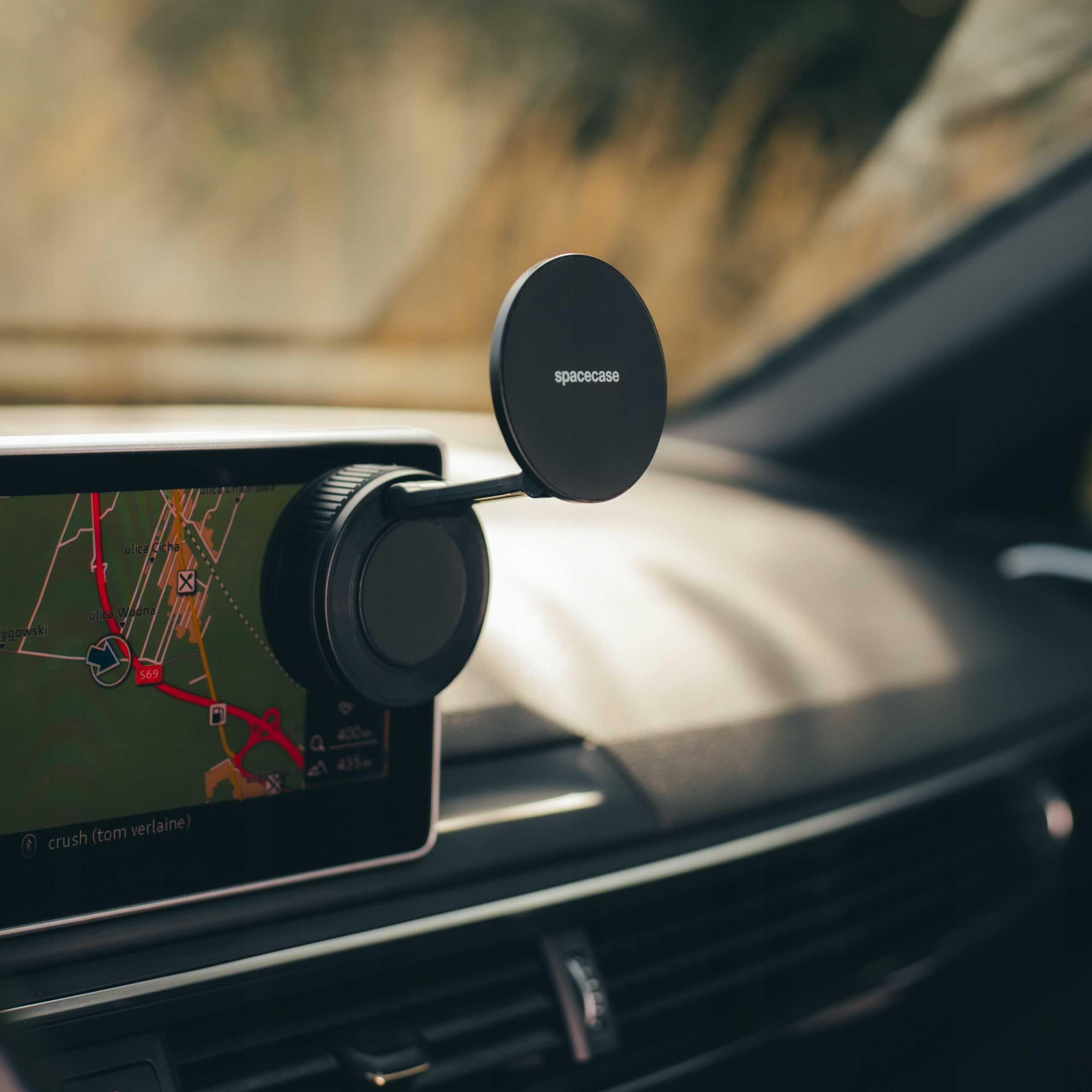 Wnętrze samochodu z ekranem nawigacji i uchwytem na telefon. Czarny uchwyt na telefon 'spacecase' jest przymocowany.