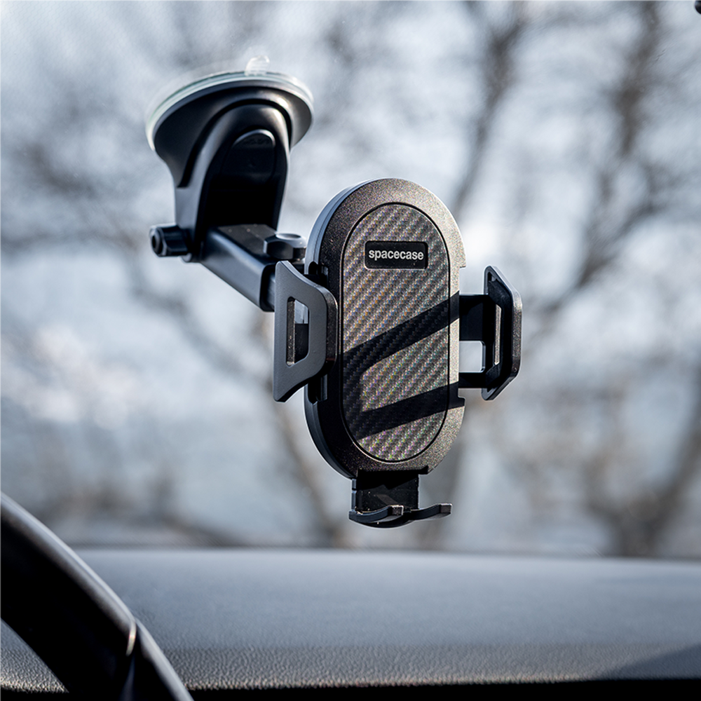 Czarny uchwyt na telefon samochodowy przymocowany do przedniej szyby. Uchwyt ma fakturę włókna węglowego i widoczna jest nazwa marki 'spacecase'.
