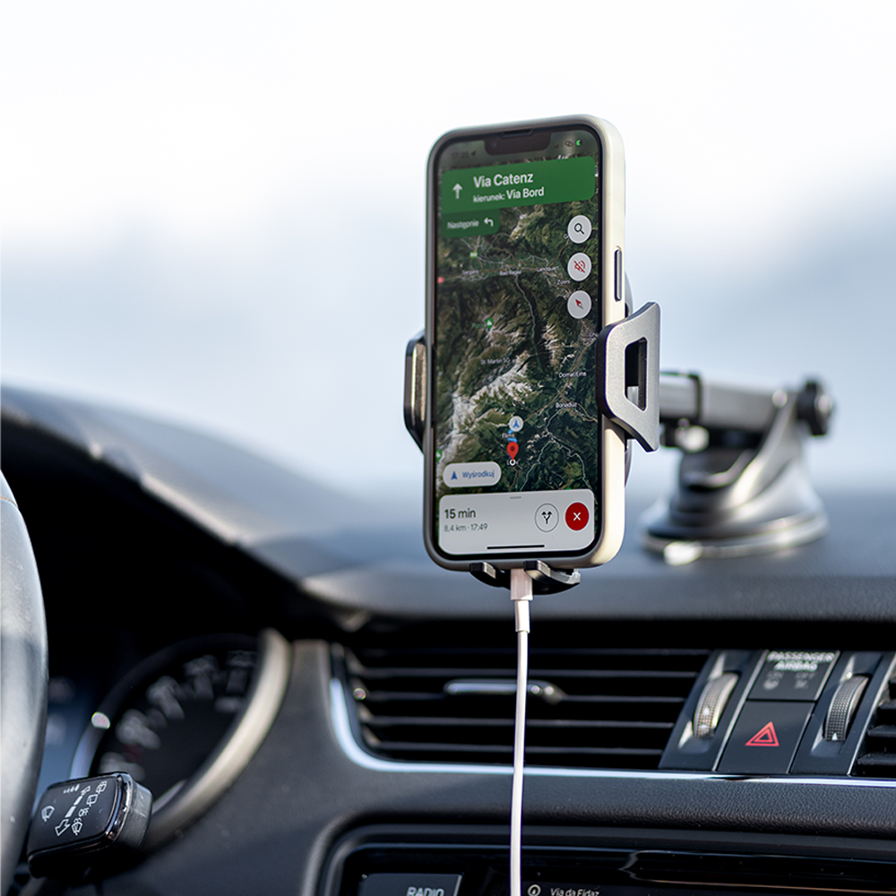 Telefon wyświetla mapę z wskazówkami. Telefon jest w uchwycie samochodowym na desce rozdzielczej.