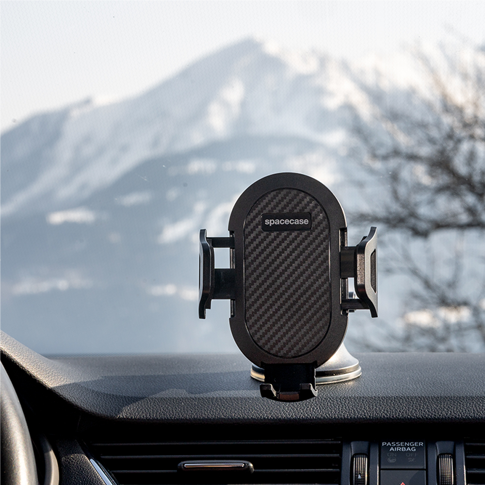 Czarny uchwyt na telefon z napisem "spacecase" jest zamontowany na desce rozdzielczej samochodu, z widokiem na góry przez przednią szybę.