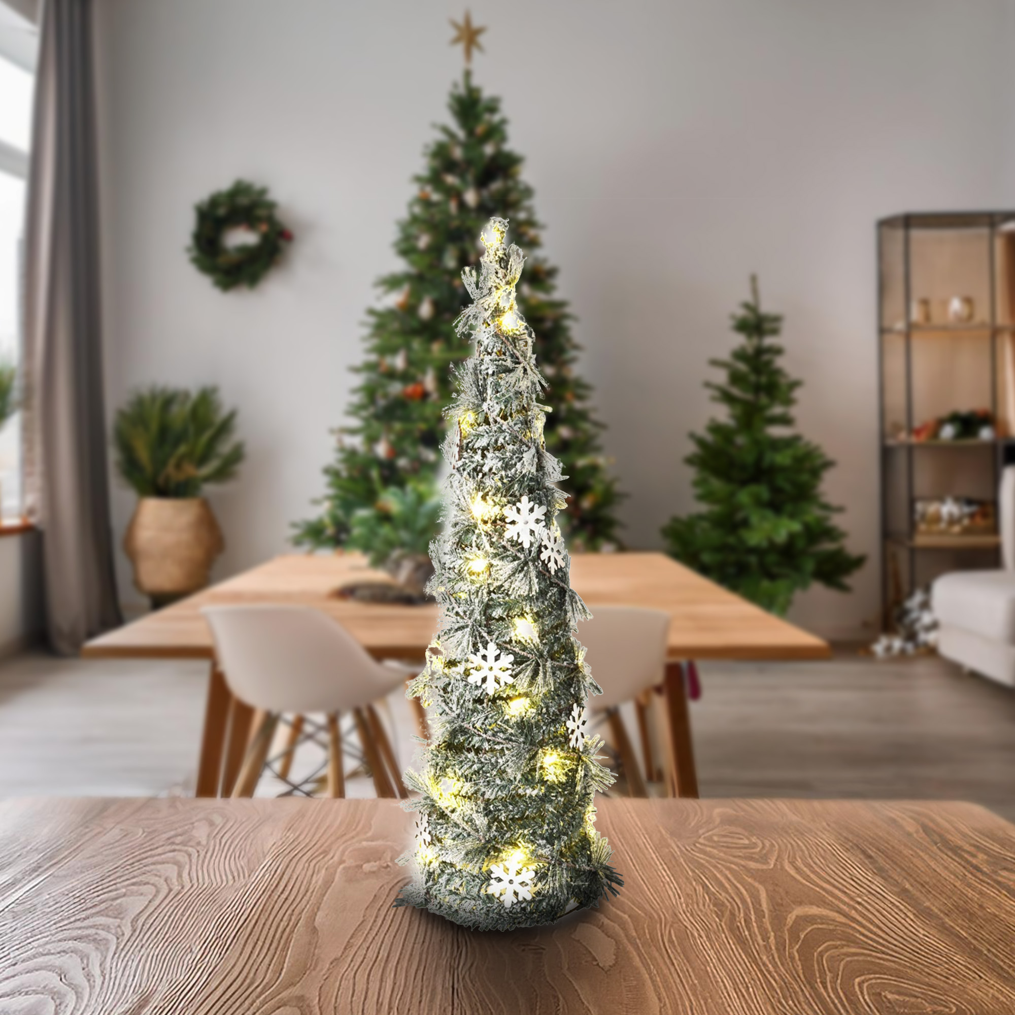 Un árbol de Navidad decorado sobre una mesa de madera. El fondo muestra un comedor con otros árboles de Navidad y decoraciones.