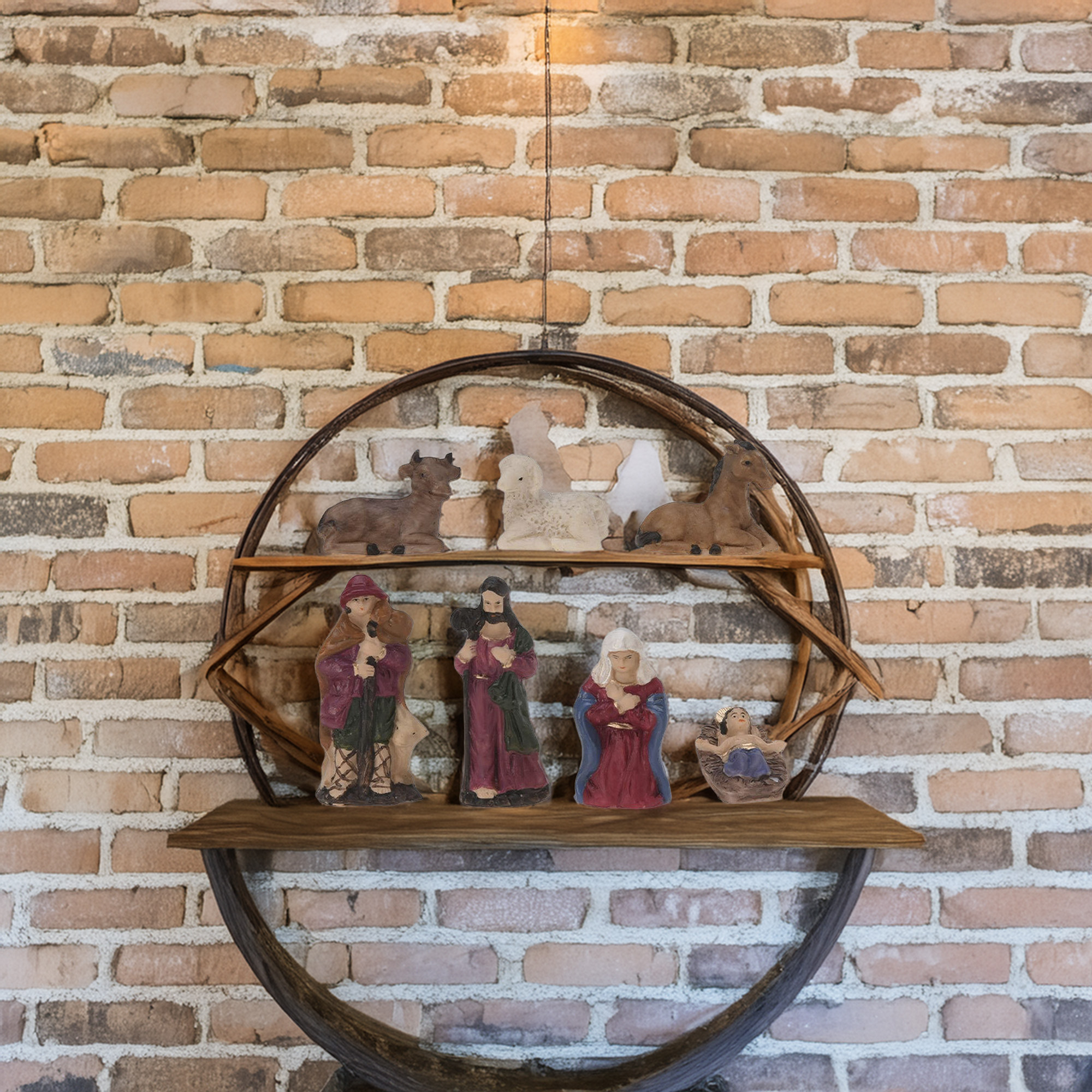 Figuras del pesebre en una estantería de madera contra una pared de ladrillo. Incluye figuras de María, José y el niño Jesús.