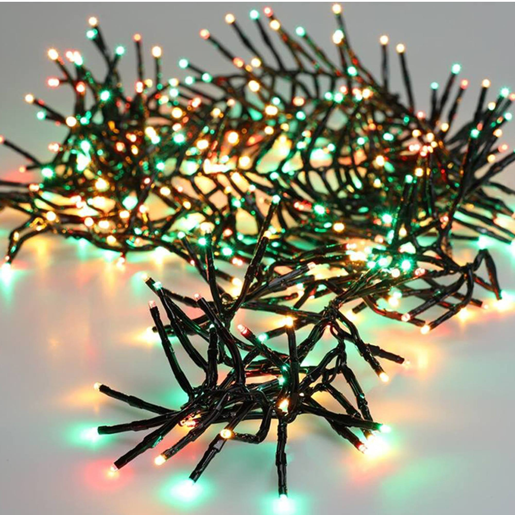Primer plano de luces navideñas. Luces verdes, rojas y amarillas en pequeños tallos negros, sobre fondo blanco.