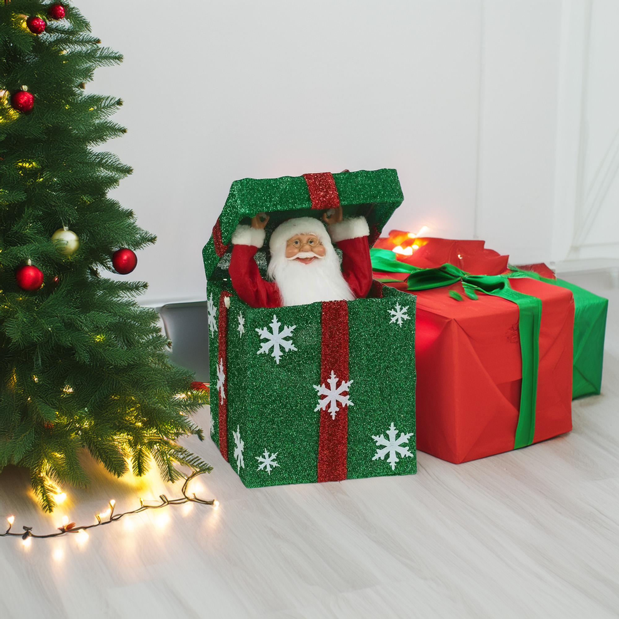 Una escena navideña muestra un árbol, Papá Noel en una caja y regalos. La caja es verde con copos de nieve y los regalos son rojos y verdes.
