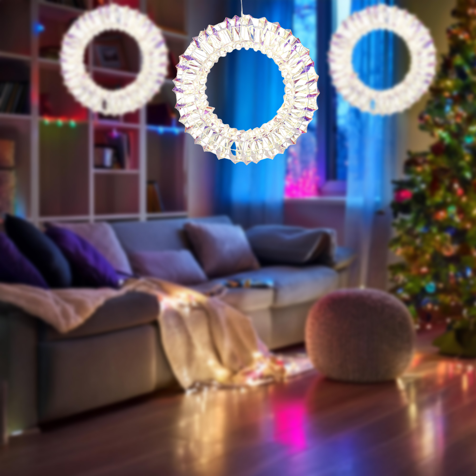 Un salón con coronas de cristal, un árbol de Navidad, un sofá y un puf. La habitación está iluminada con luces de colores.