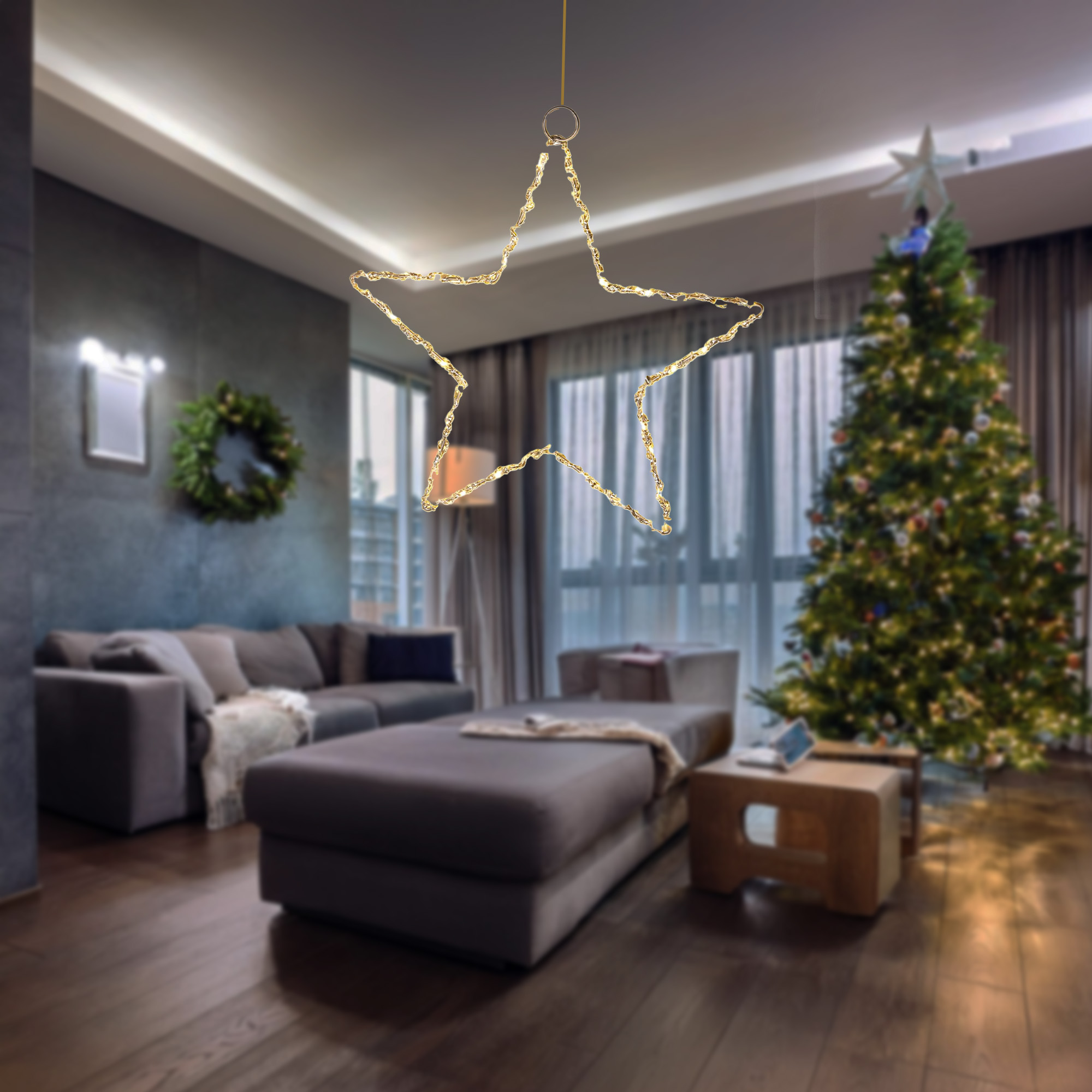 Una estrella decorativa iluminada cuelga en una sala de estar. Un árbol de Navidad y un sofá son visibles en el fondo.