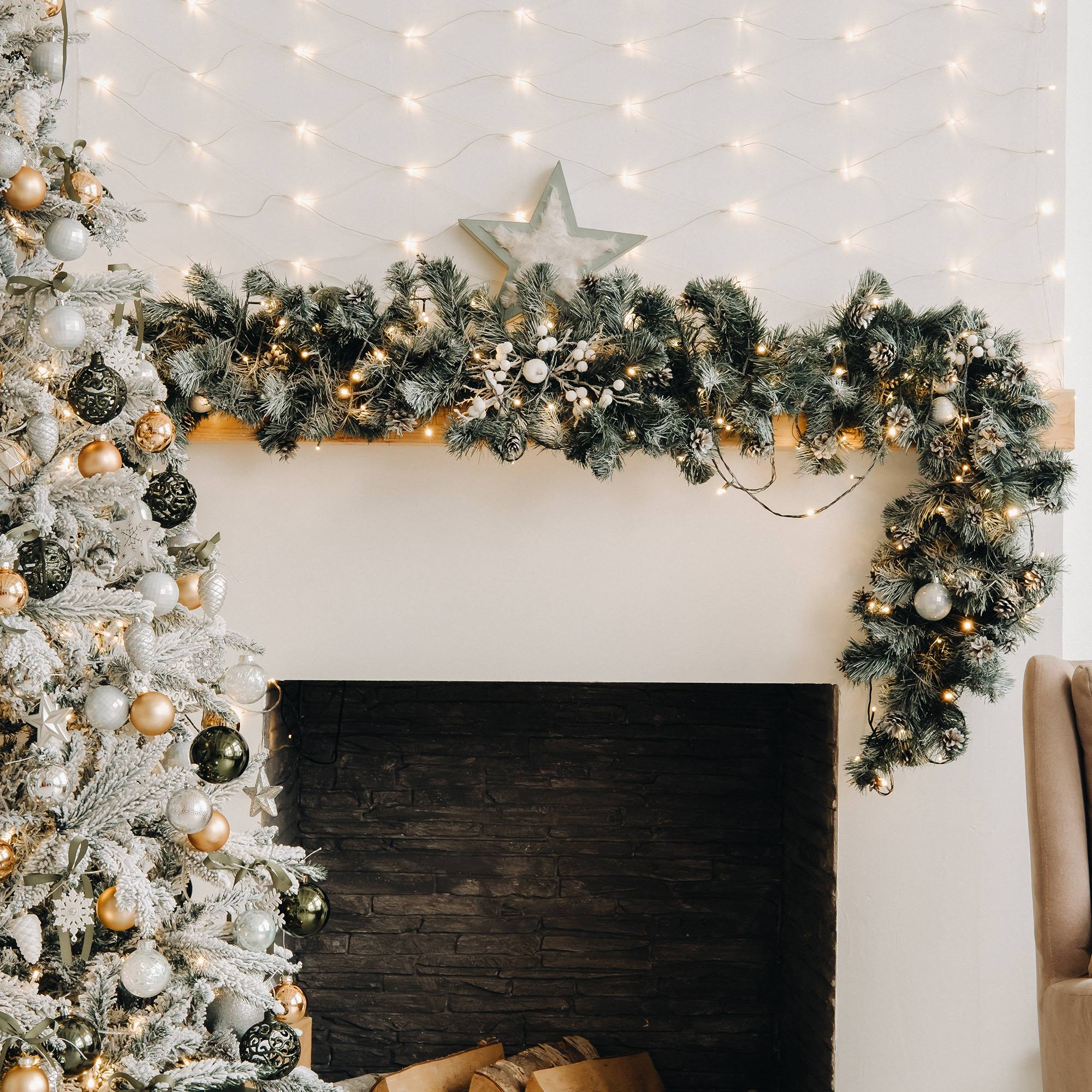 Un árbol de Navidad decorado con adornos, guirnalda sobre una chimenea, luces de cadena. Una estrella adorna la repisa.