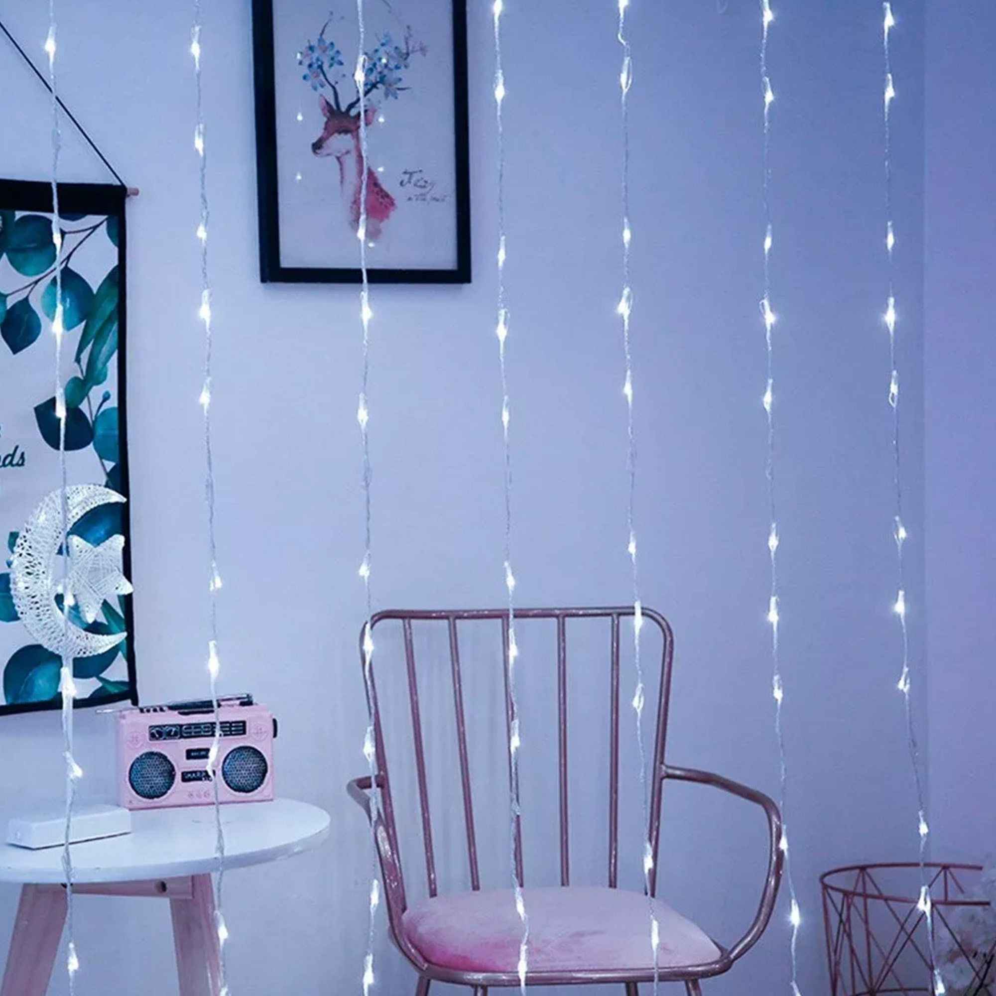 Decoración de habitación con luces de cadena, una silla rosa, una radio, obras de arte y una cesta de alambre. Iluminación suave.