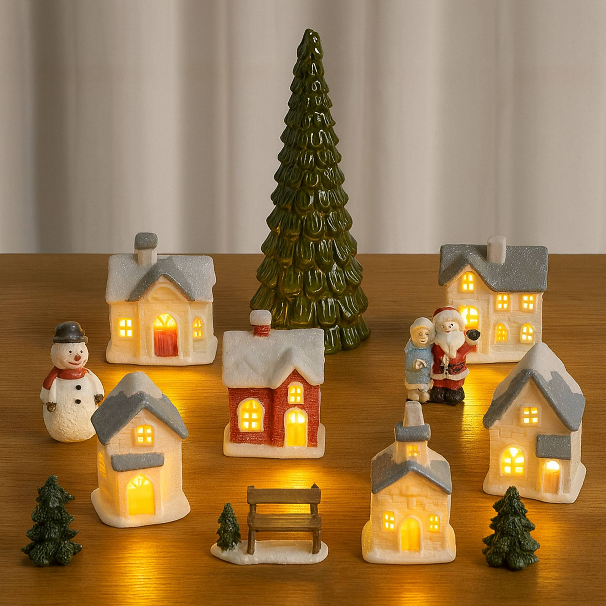 Escena de un pueblo navideño con casas iluminadas, muñeco de nieve, Papá Noel, árboles y banco sobre madera. Festivo.