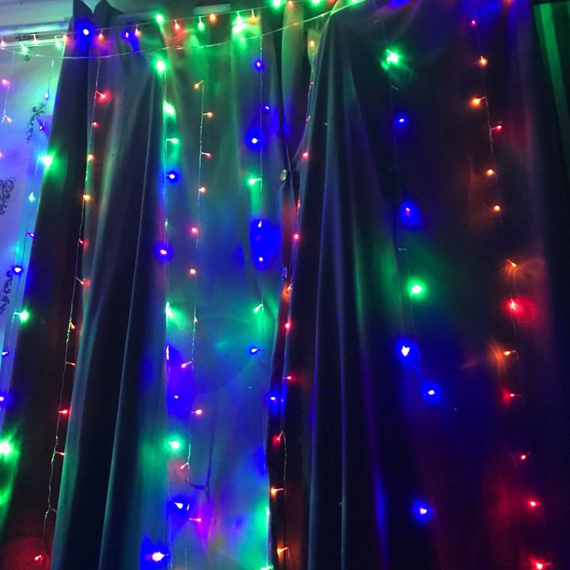 Cortinas oscuras con luces de cadena rojas, verdes y azules. Las luces están encendidas, creando ambiente festivo.
