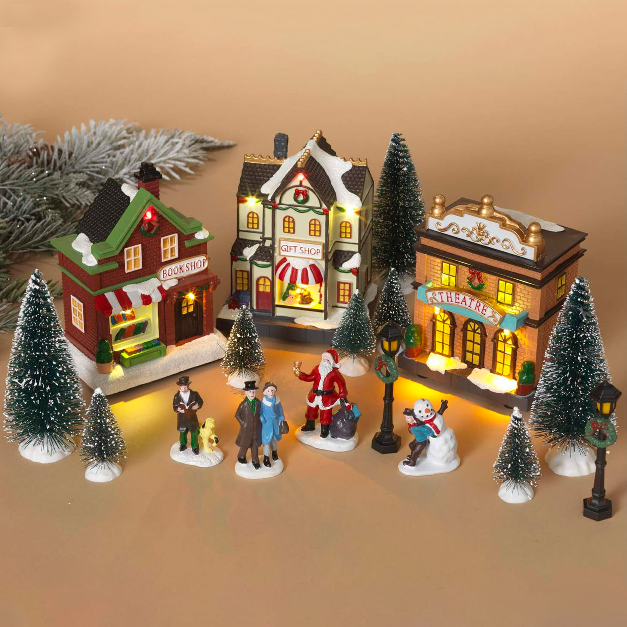 Pueblo navideño en miniatura con librería, tienda de regalos, teatro, Papá Noel, muñeco de nieve, gente, farolas y árboles de Navidad.